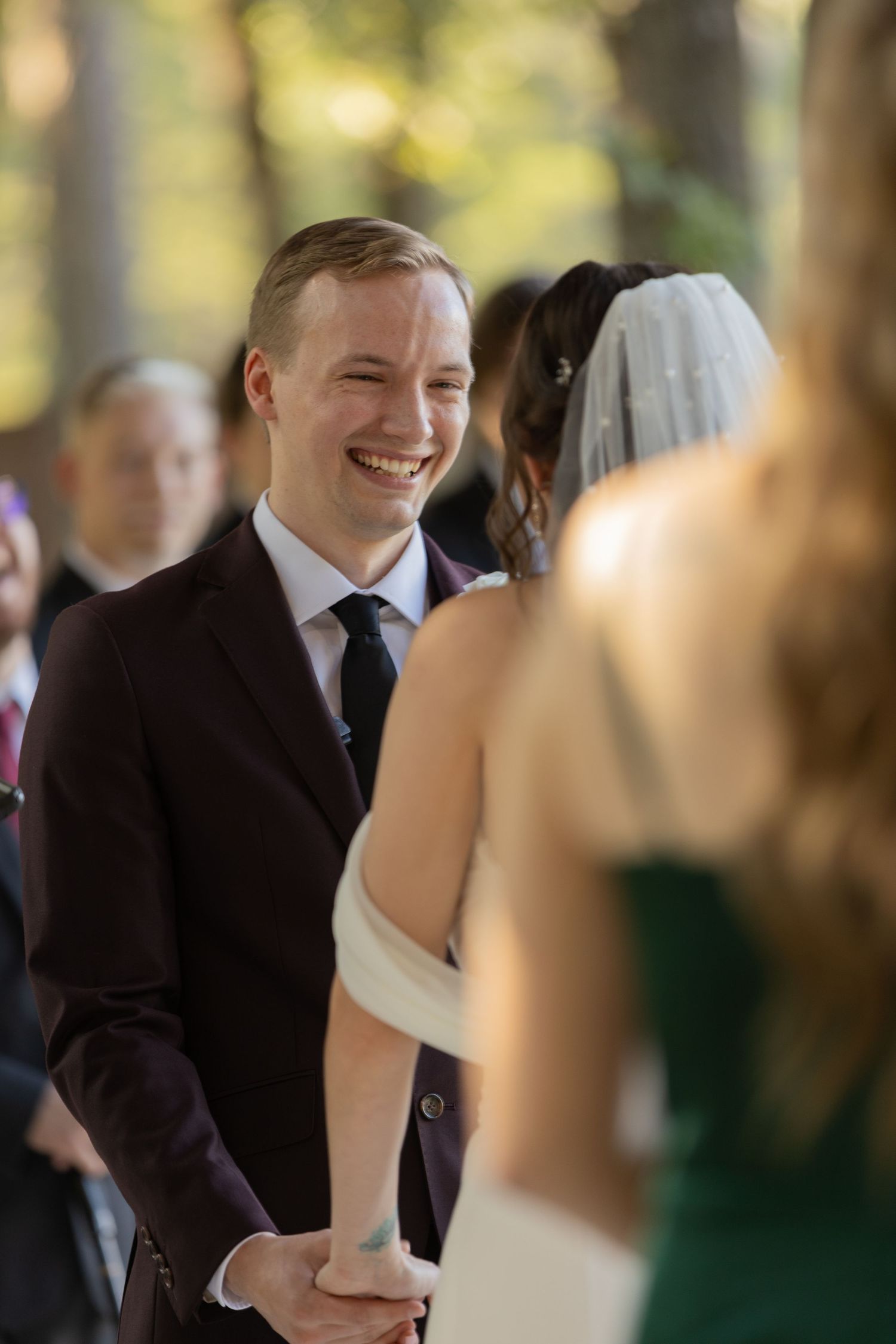 Joyful moment captured during outdoor wedding ceremony with guests in background.