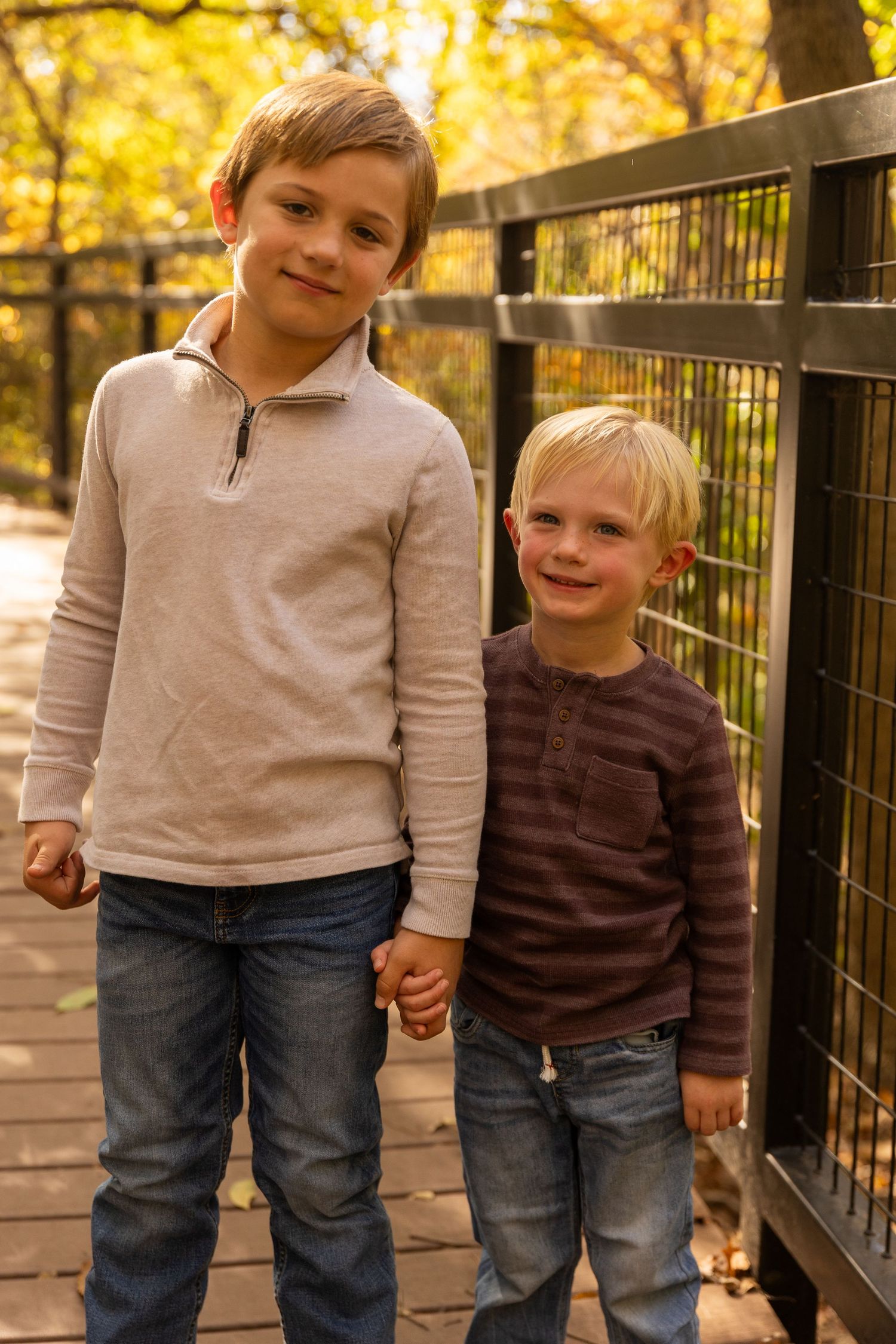Children stand together on wooden boardwalk wearing casual autumn attire.
