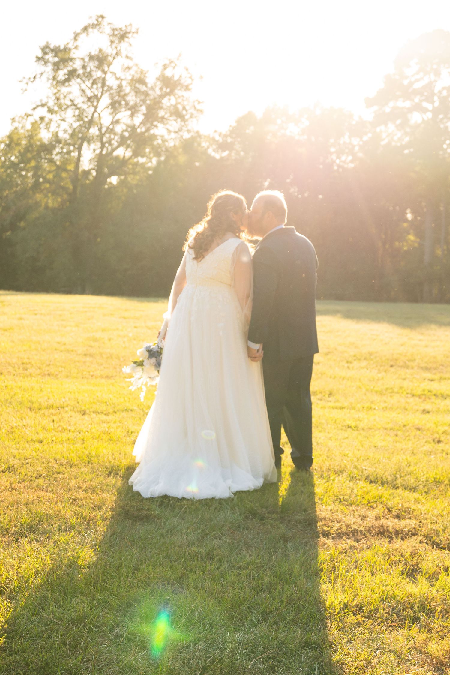 Sunset wedding portraits in a golden field with dramatic backlighting.