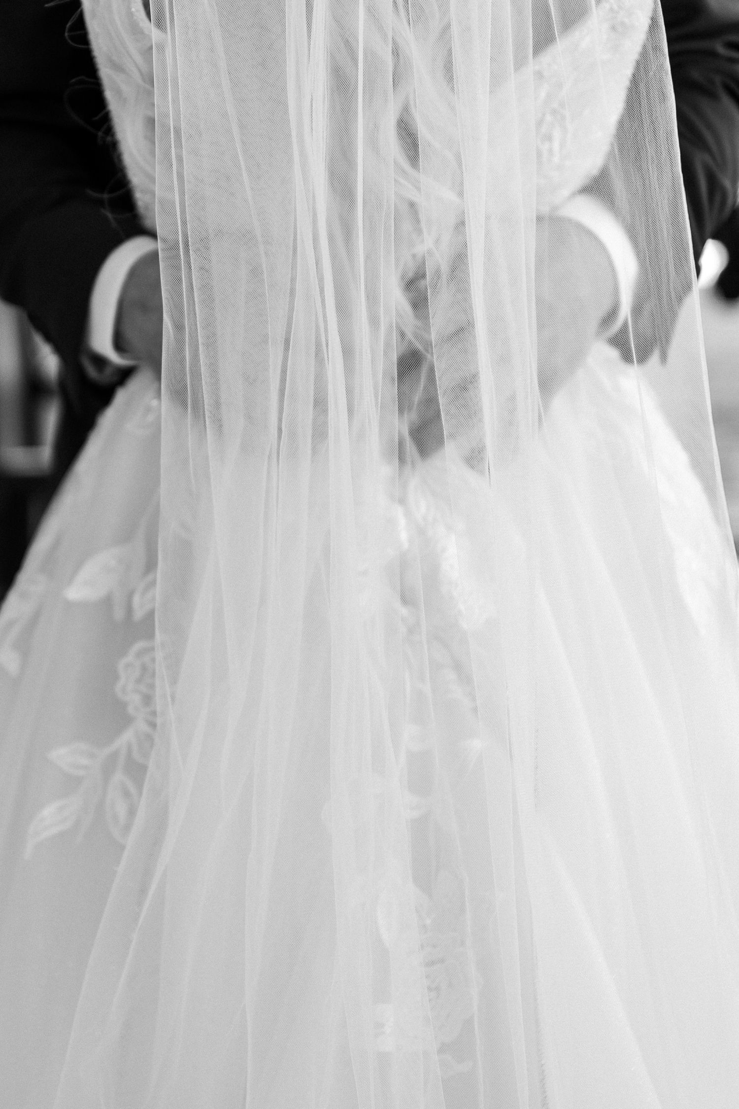 Close-up details of a flowing white wedding veil with delicate lace trim and embroidery.