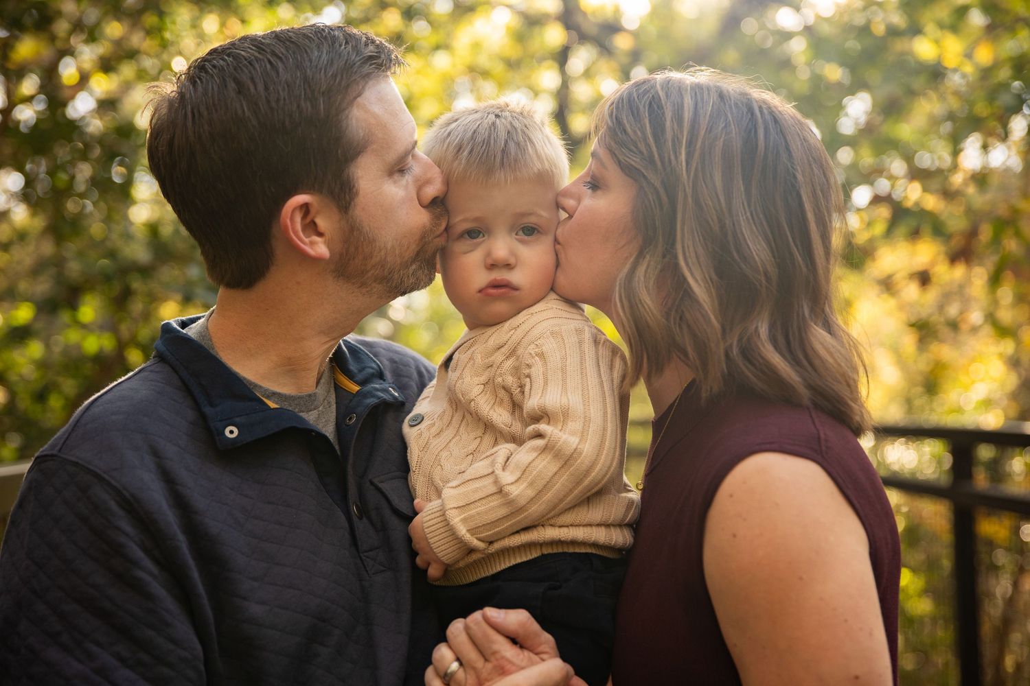 Intimate family portrait captured in golden autumn light on wooden bridge.