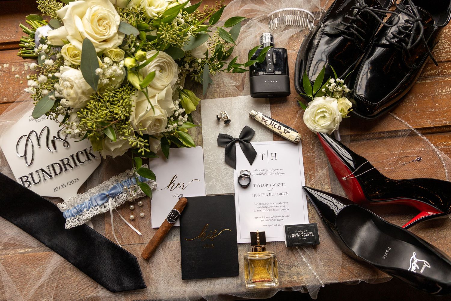 Wedding details including white roses, invitations and decorative elements on wooden surface.