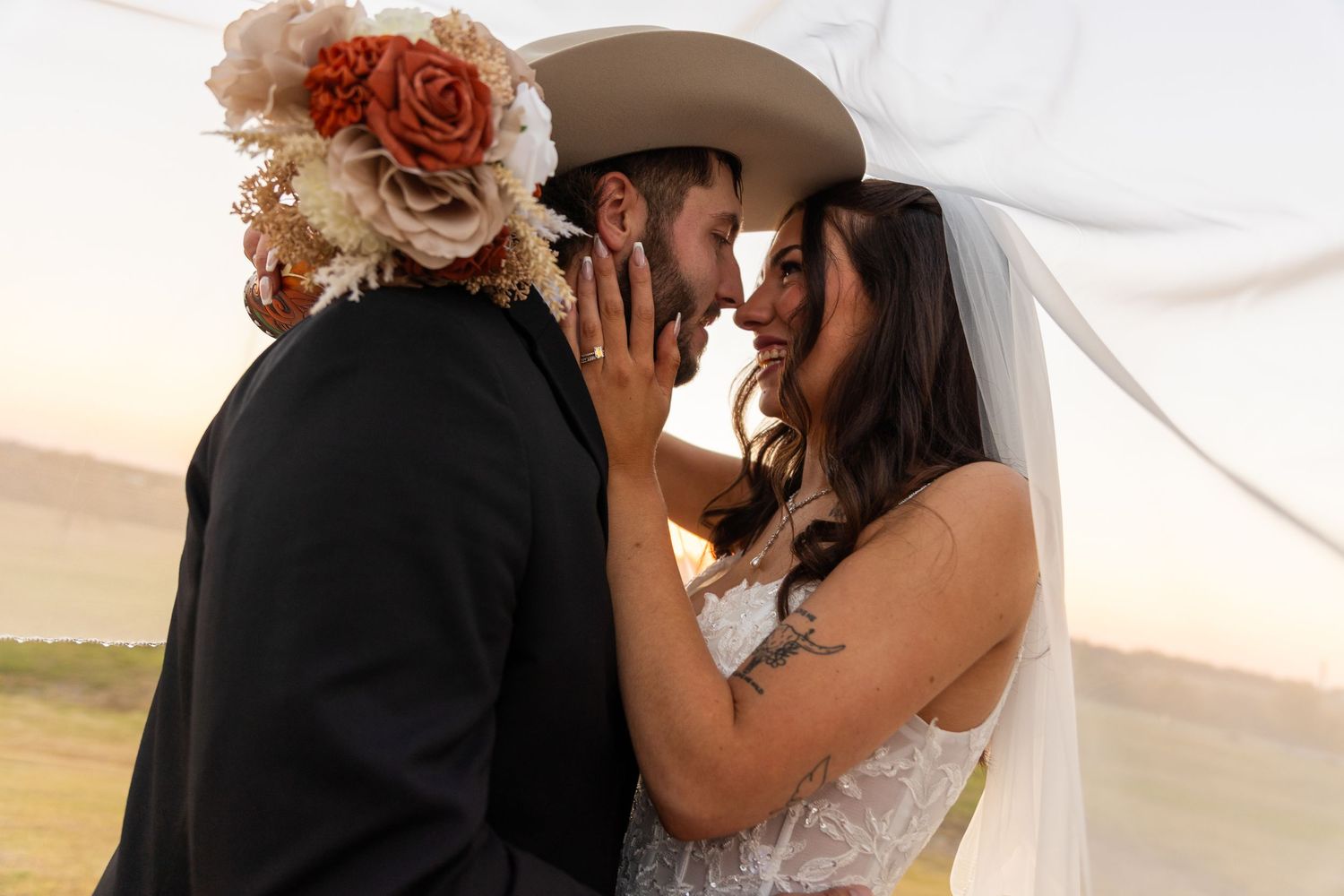 Romantic sunset portraits of newlyweds with flowing veil against golden light.