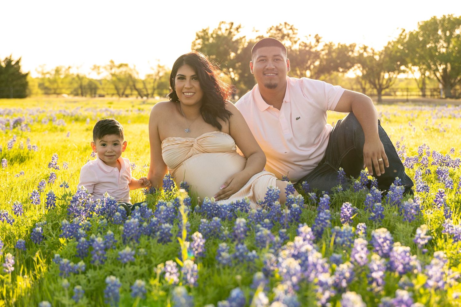 Family photoshoot in a field of vibrant bluebonnets during golden hour sunset.