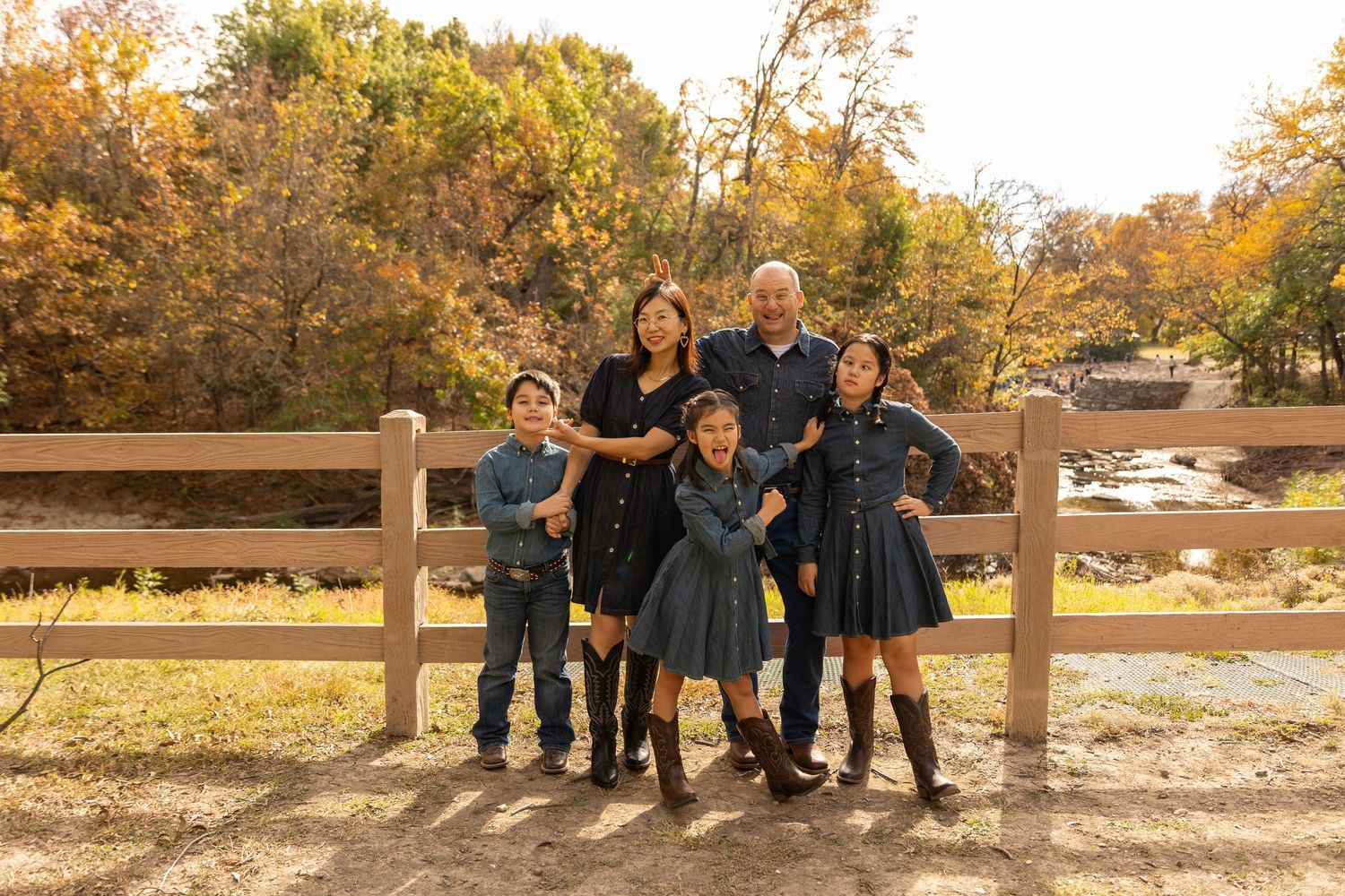 Family group posed together against a wooden fence during autumn.
