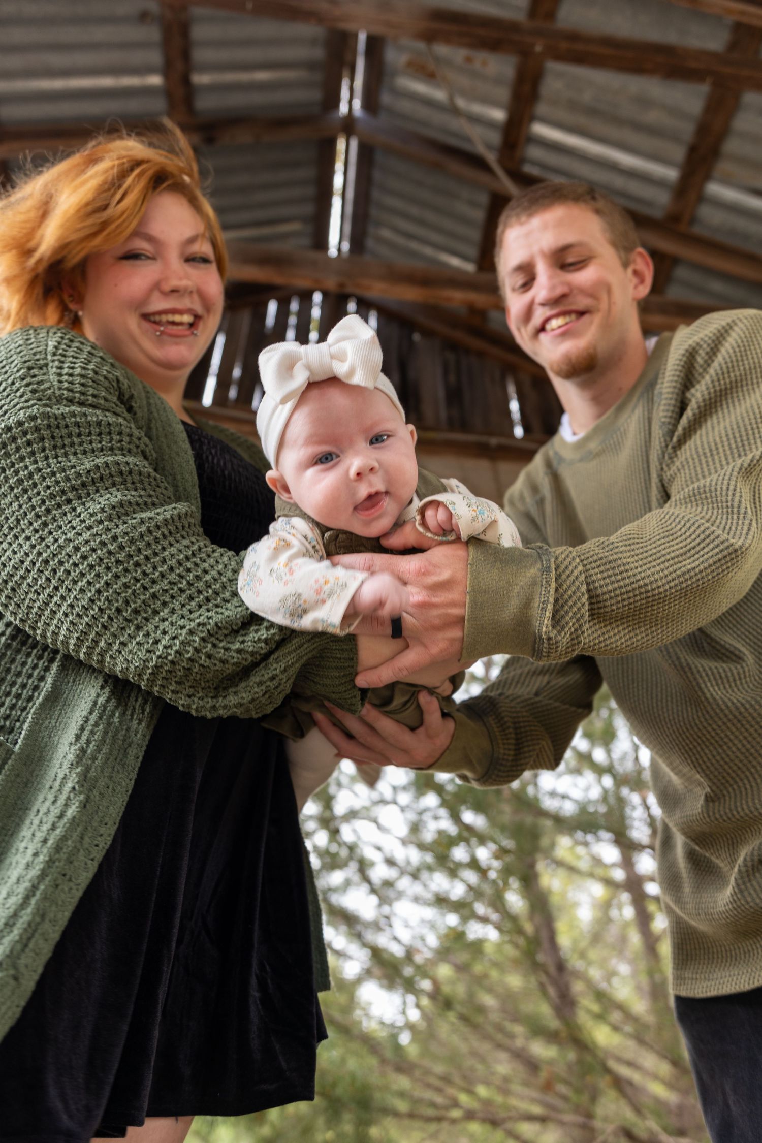 Sweet moment between parents and baby in rustic barn setting with natural light.