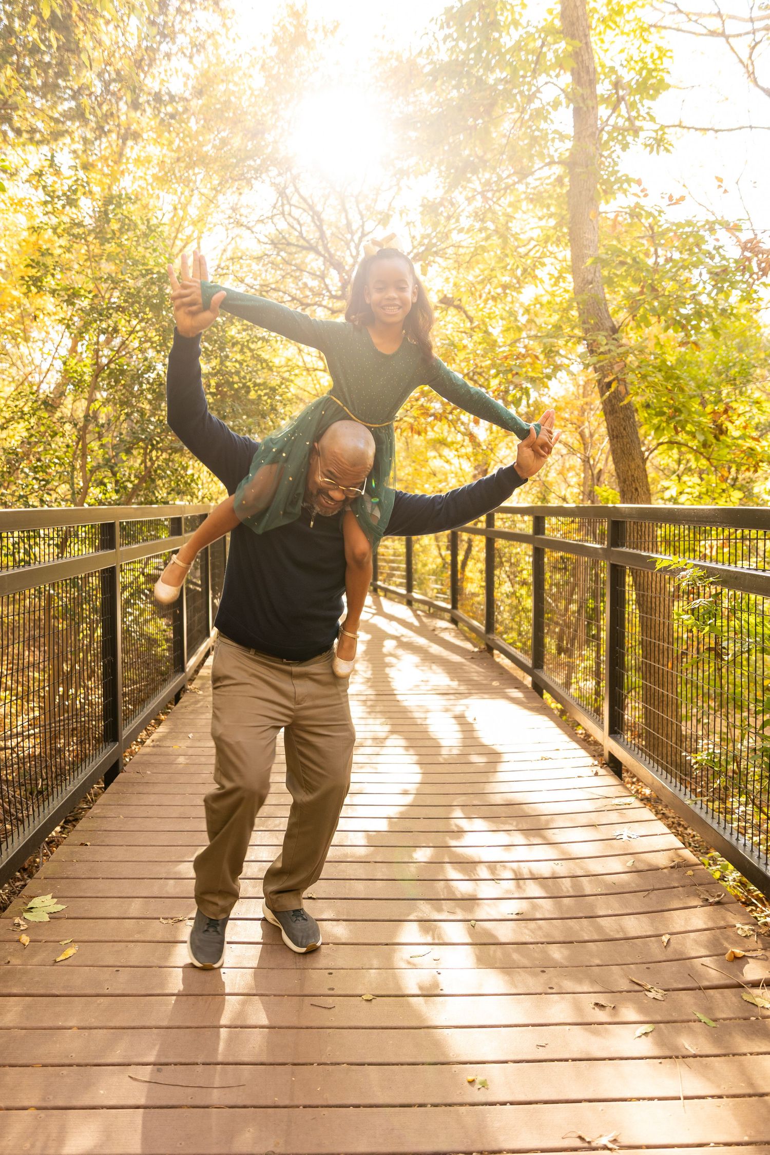 Playful moment captured on a wooden bridge with sunlit trees in the background.