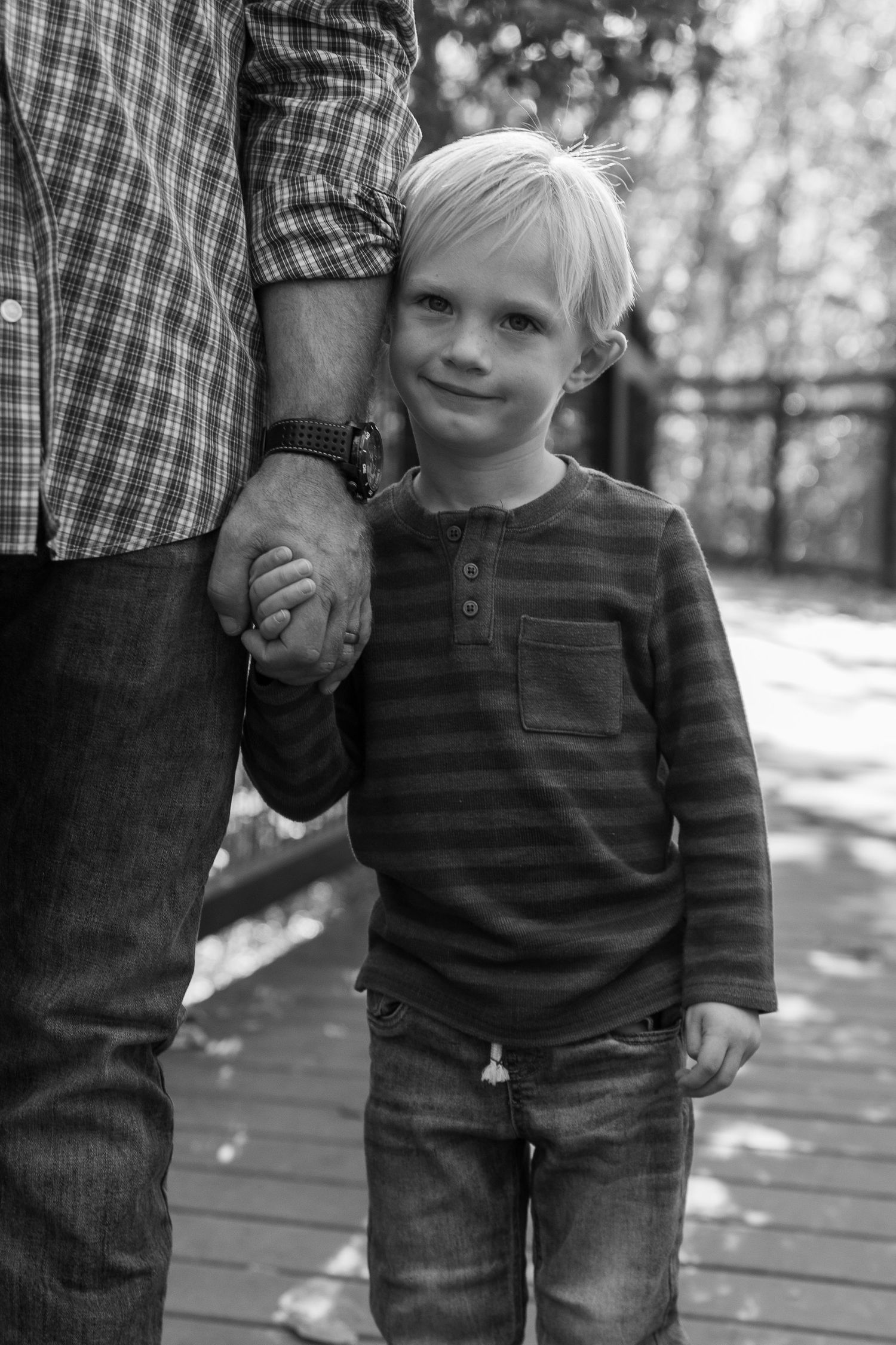 Black and white series capturing tender moments between parent and child on wooden walkway.
