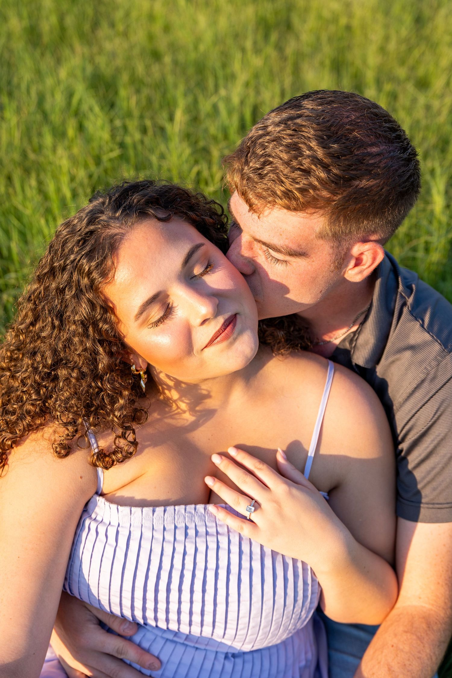A tender moment between a couple in a sunlit field with golden hour lighting.