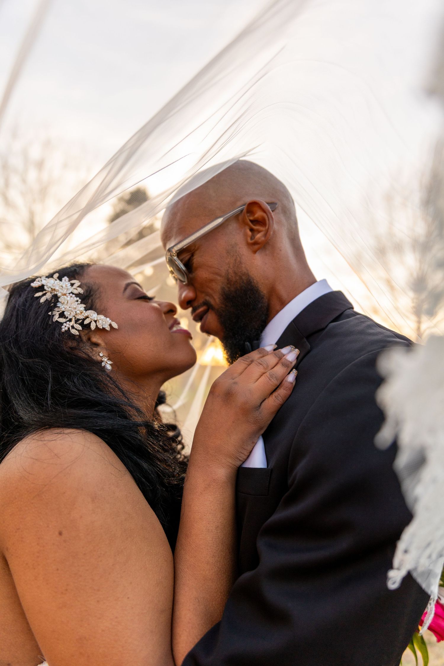 Intimate wedding portrait silhouetted against sunset sky.