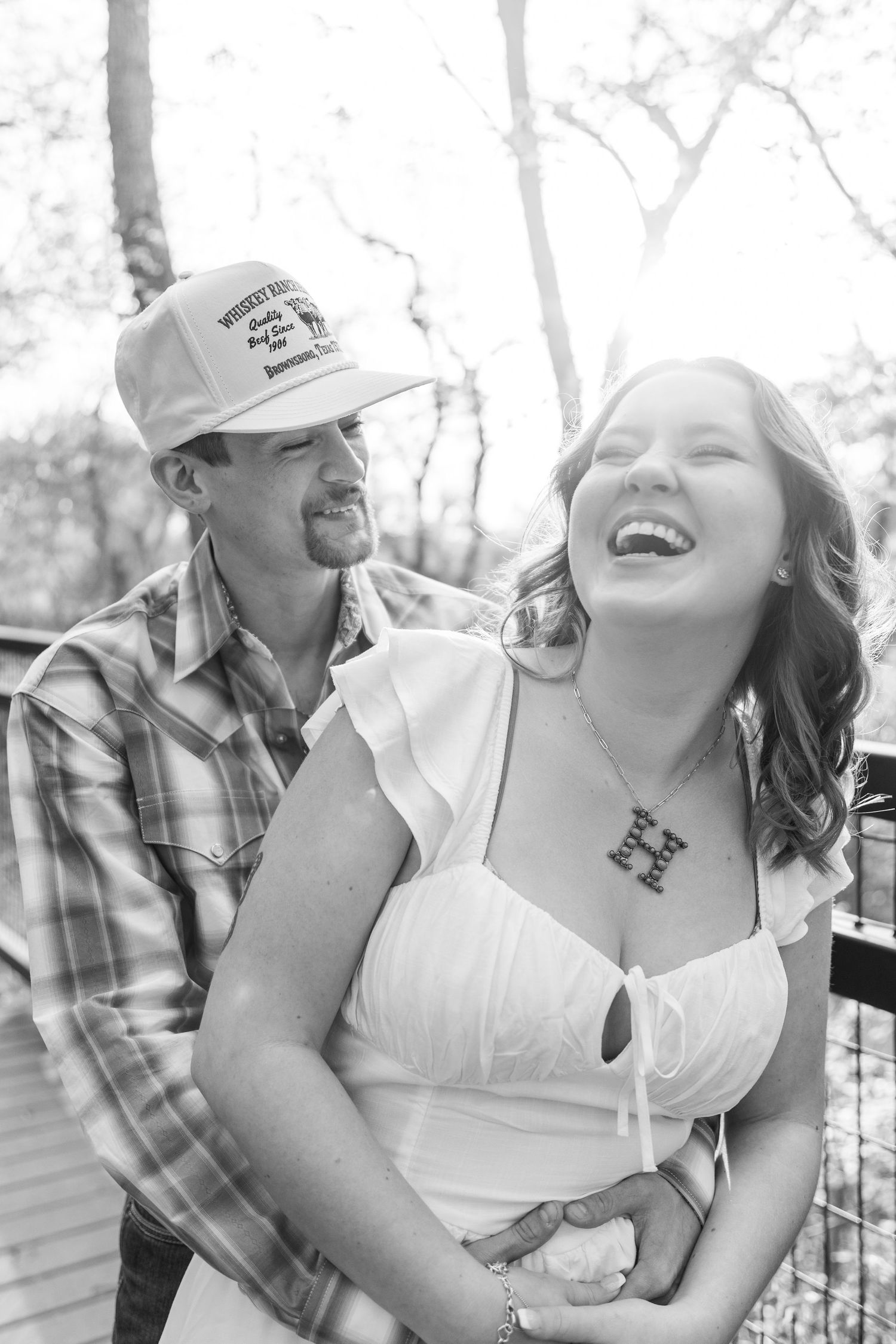 A candid black and white photo of a laughing couple on a wooden deck.