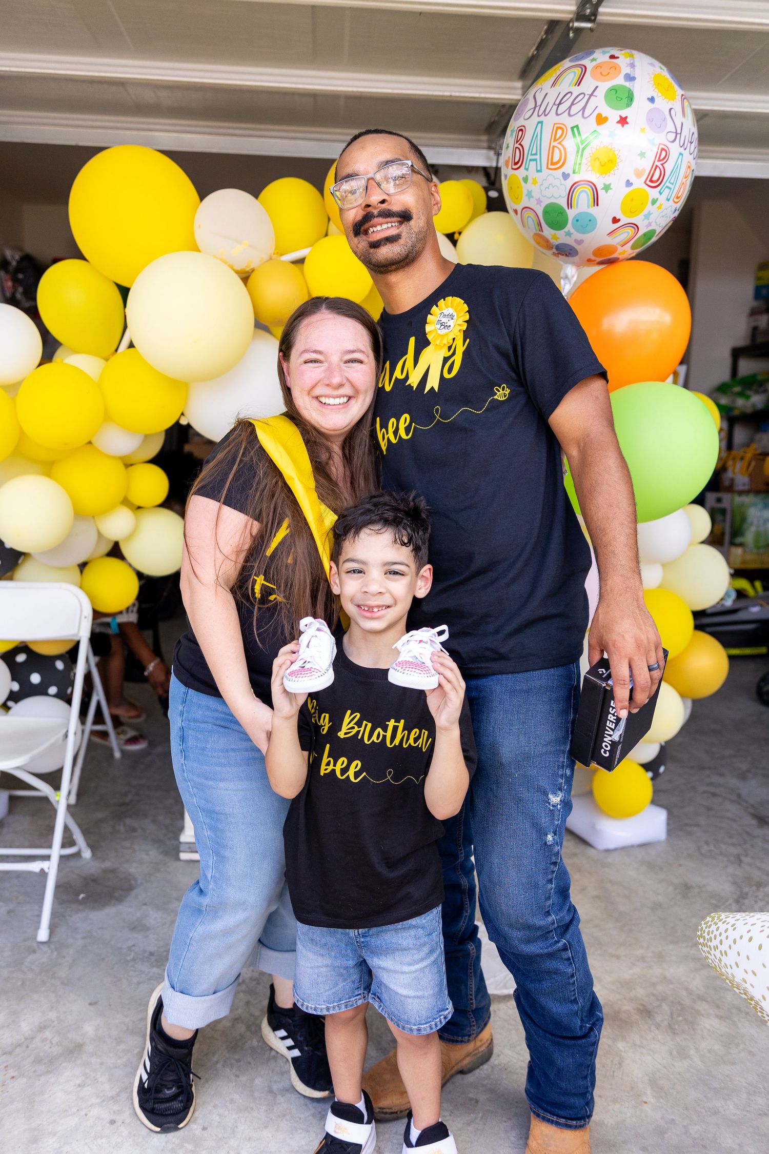 Family celebration with colorful yellow and orange balloons decorating a garage or indoor space.
