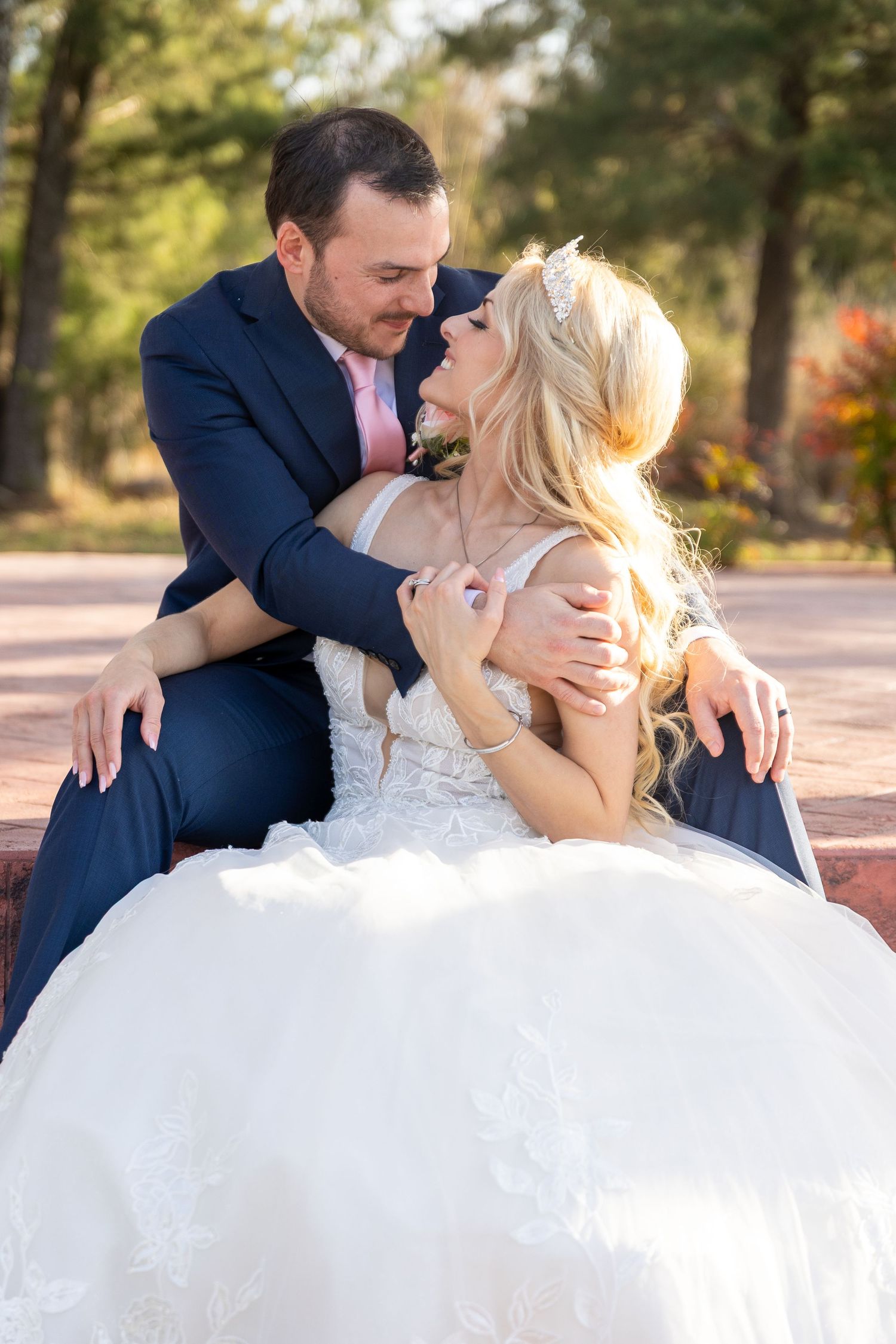 Romantic wedding couple portraits with flowing white dress against outdoor backdrop.