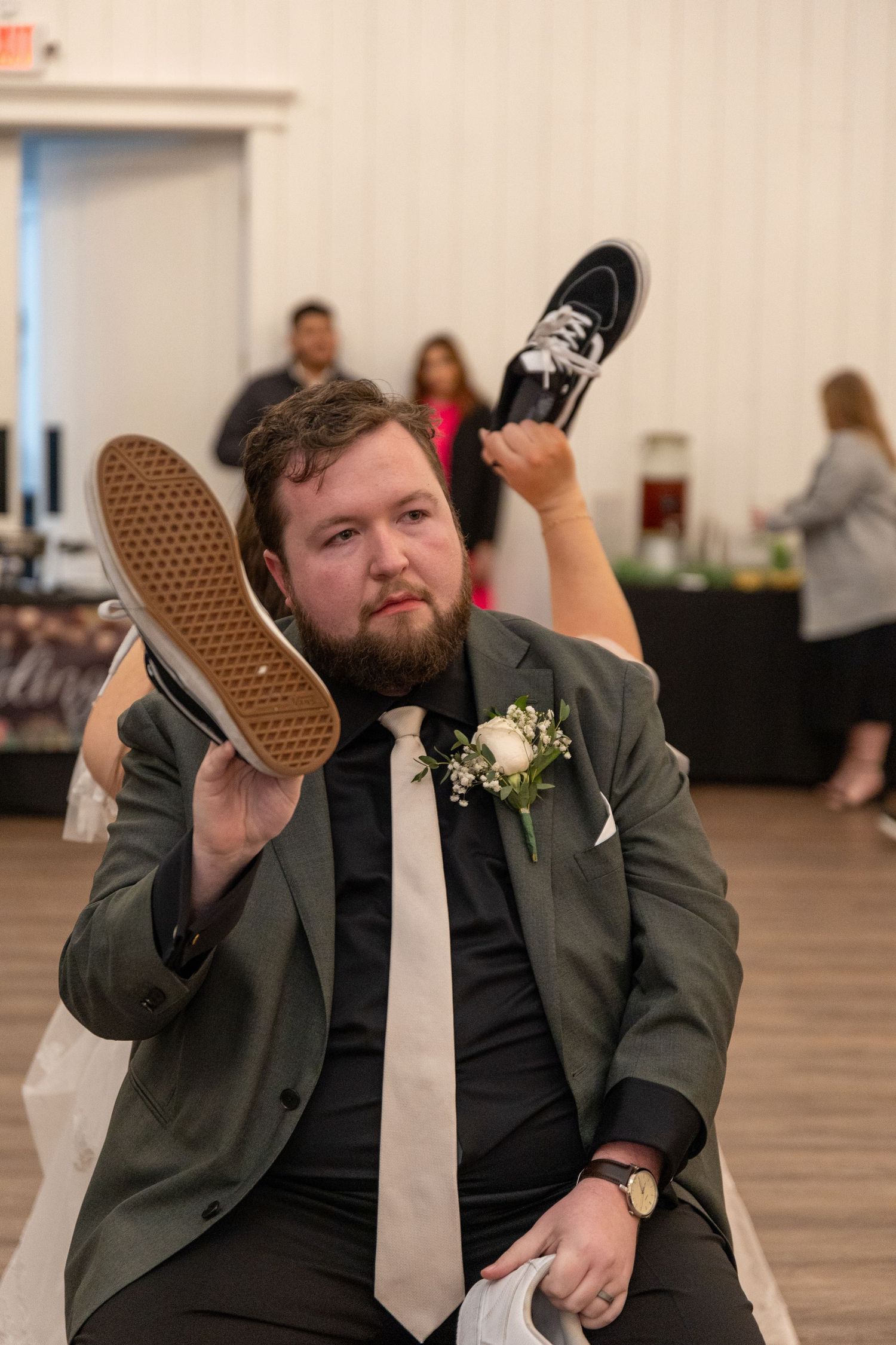Wedding guest playfully poses with shoes during reception celebration.