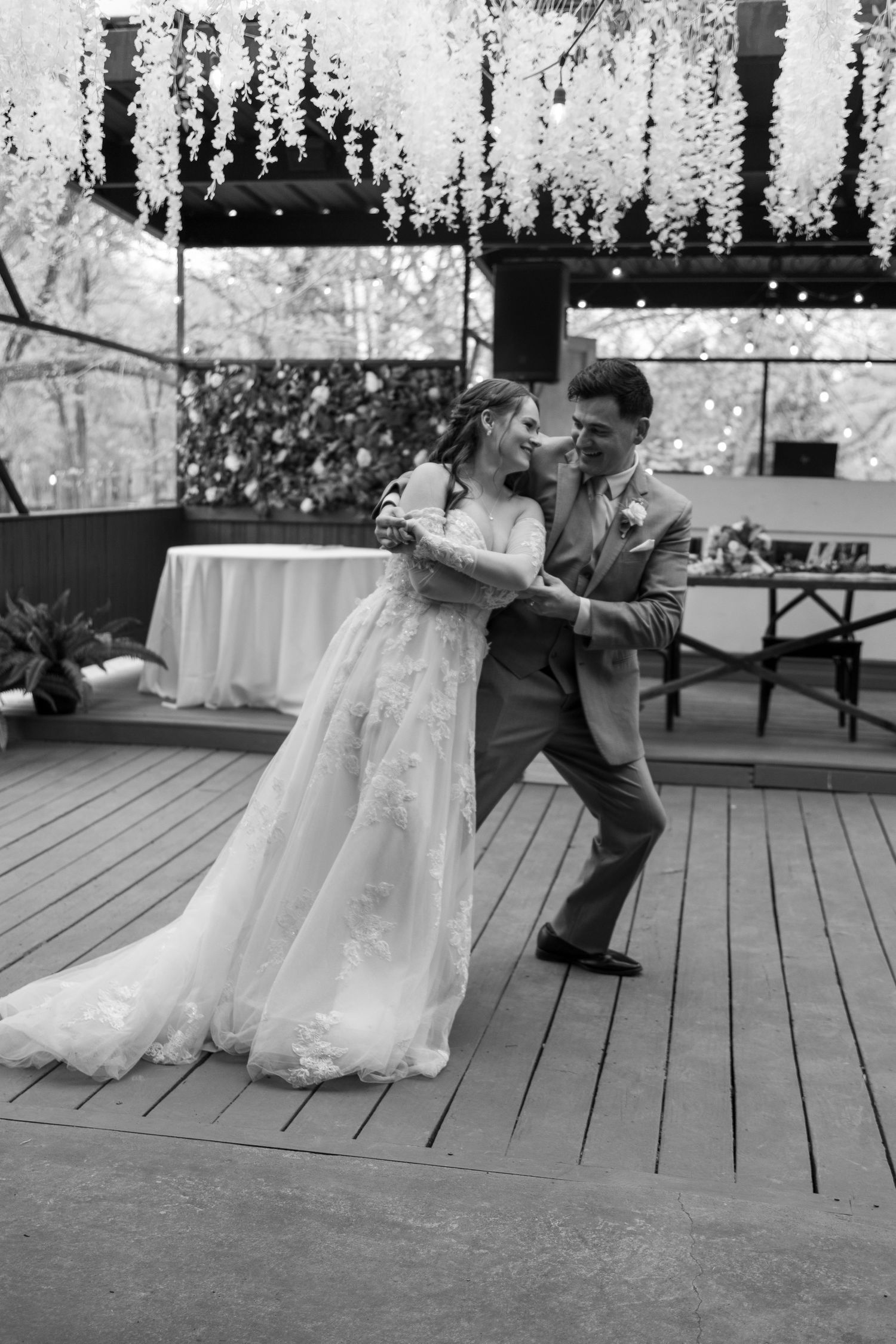 Black and white sequence of playful moments on wooden deck with wedding dress details.