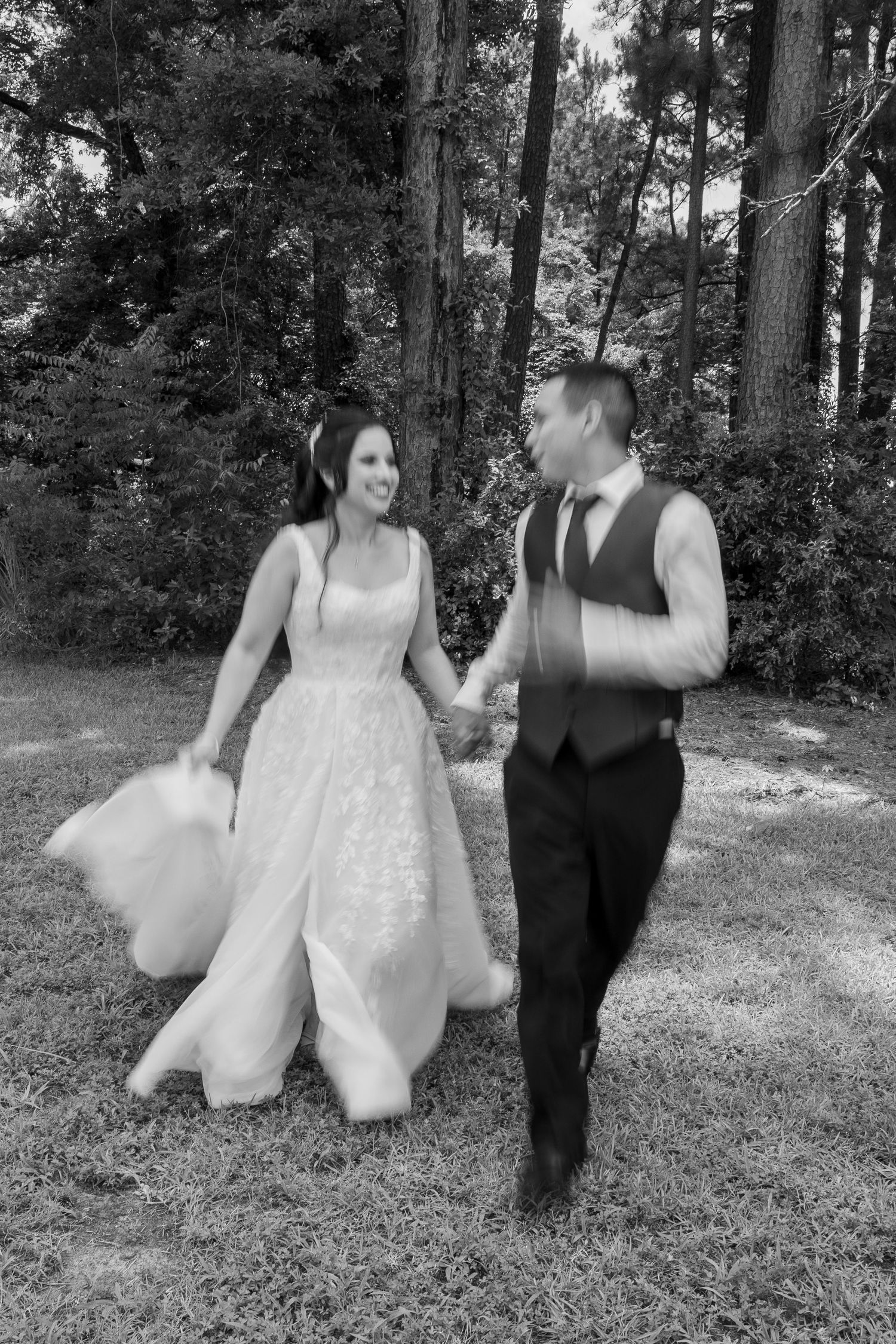 Bride and groom dancing and twirling in a wooded outdoor setting.
