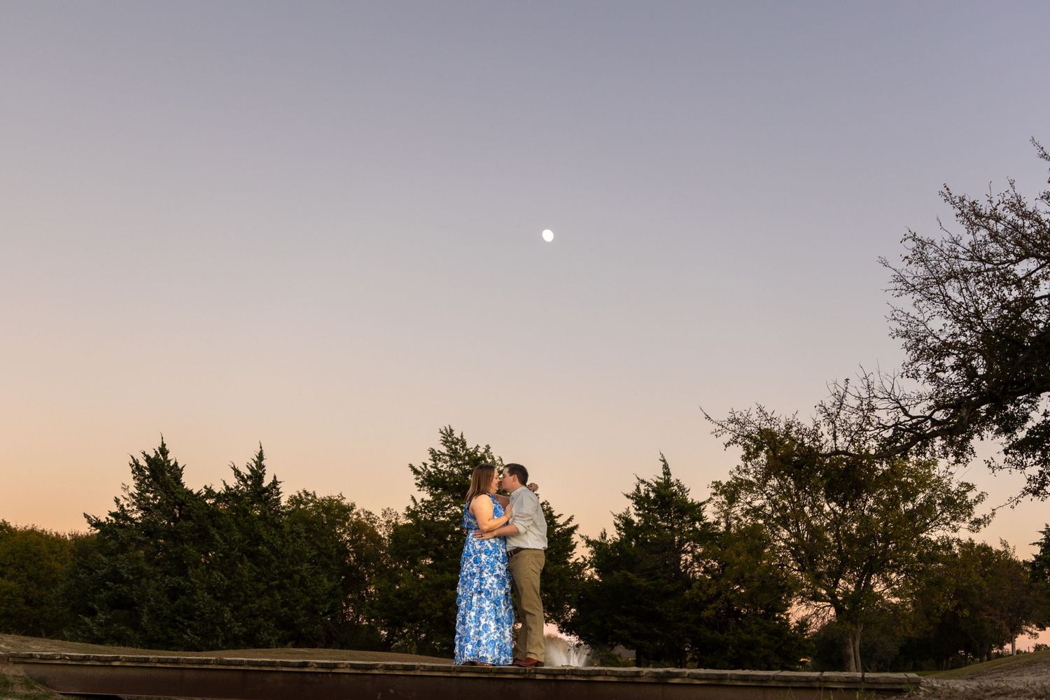 Silhouetted couple against a dusky purple sky during sunset.