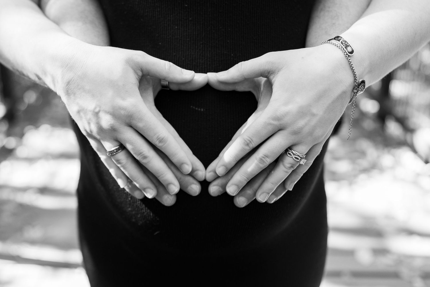 Series of hands forming heart shapes over a pregnant belly.