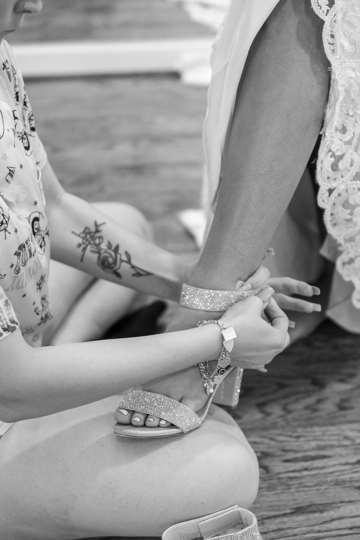 Close-up of hands putting on elegant white wedding shoes with lace details.