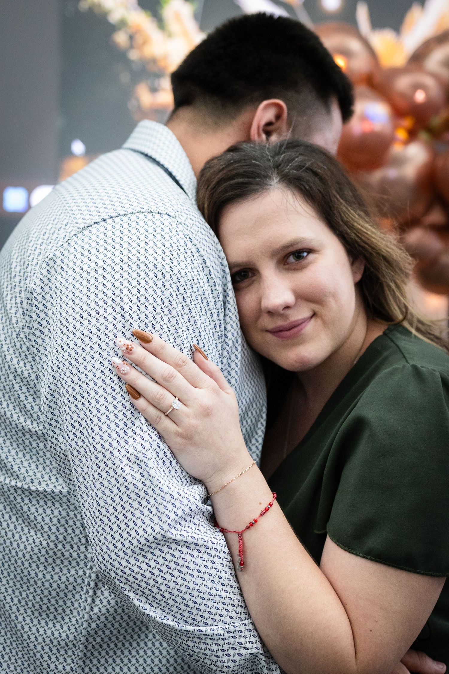 A couple shares an intimate moment during their engagement shoot with decorative lights in the background.