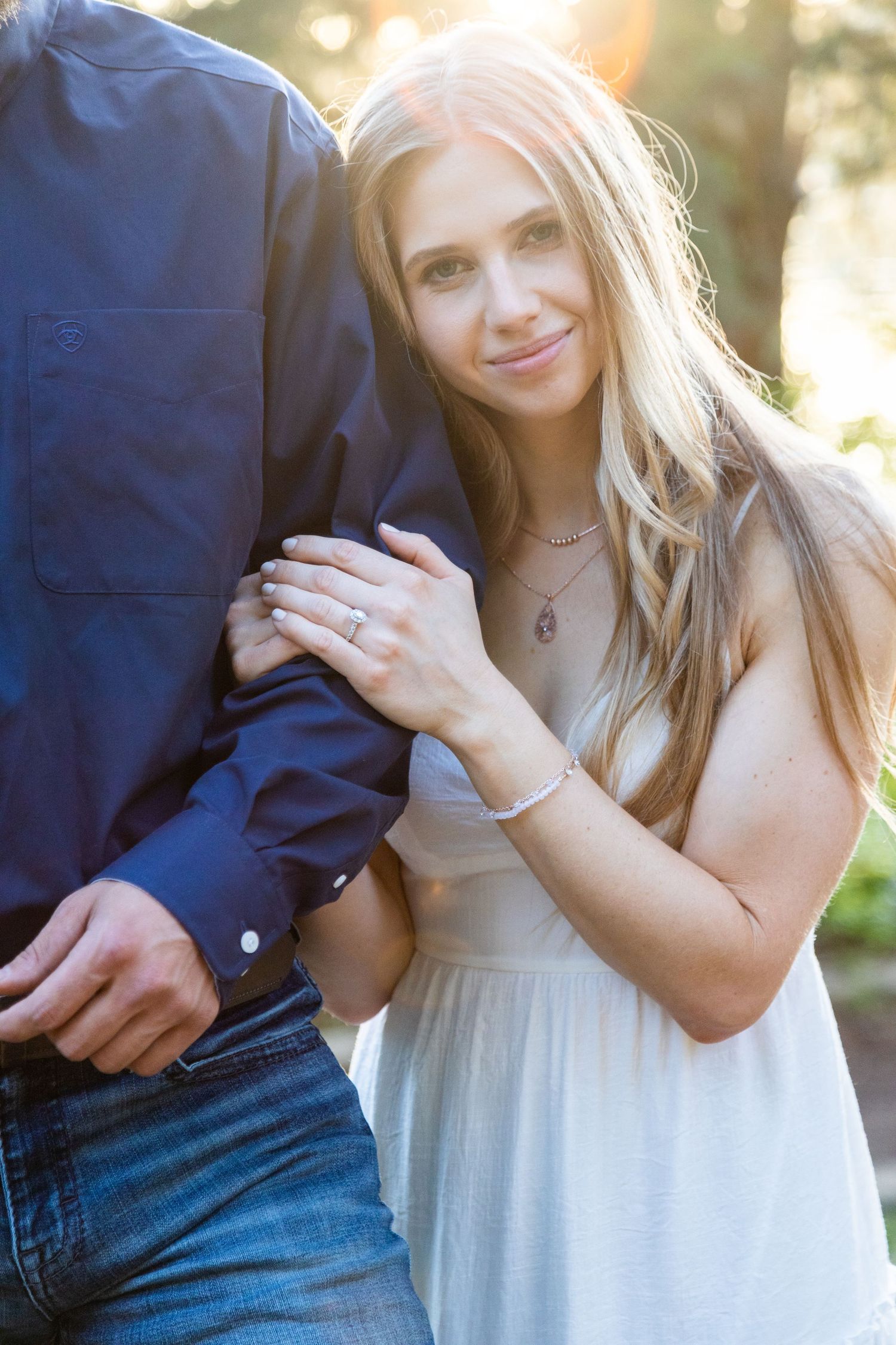 Close-up of engagement ring shown against formal attire during sunset photoshoot.