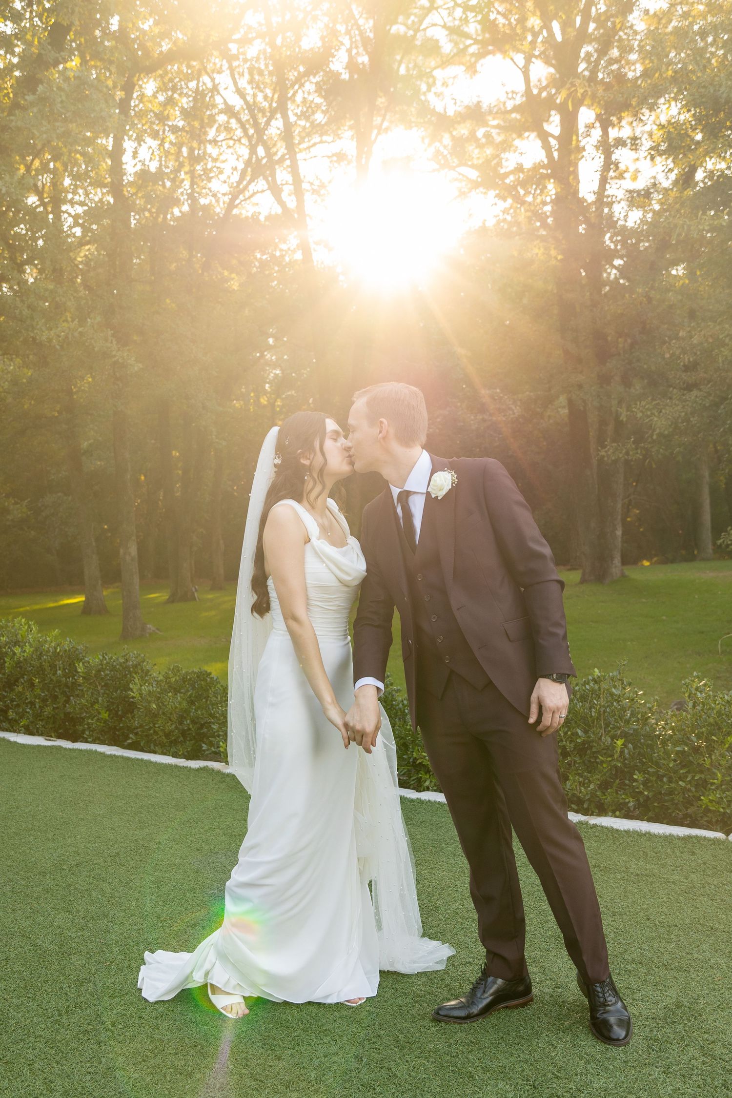 Couple walking together on a sunlit lawn during their wedding day celebration.