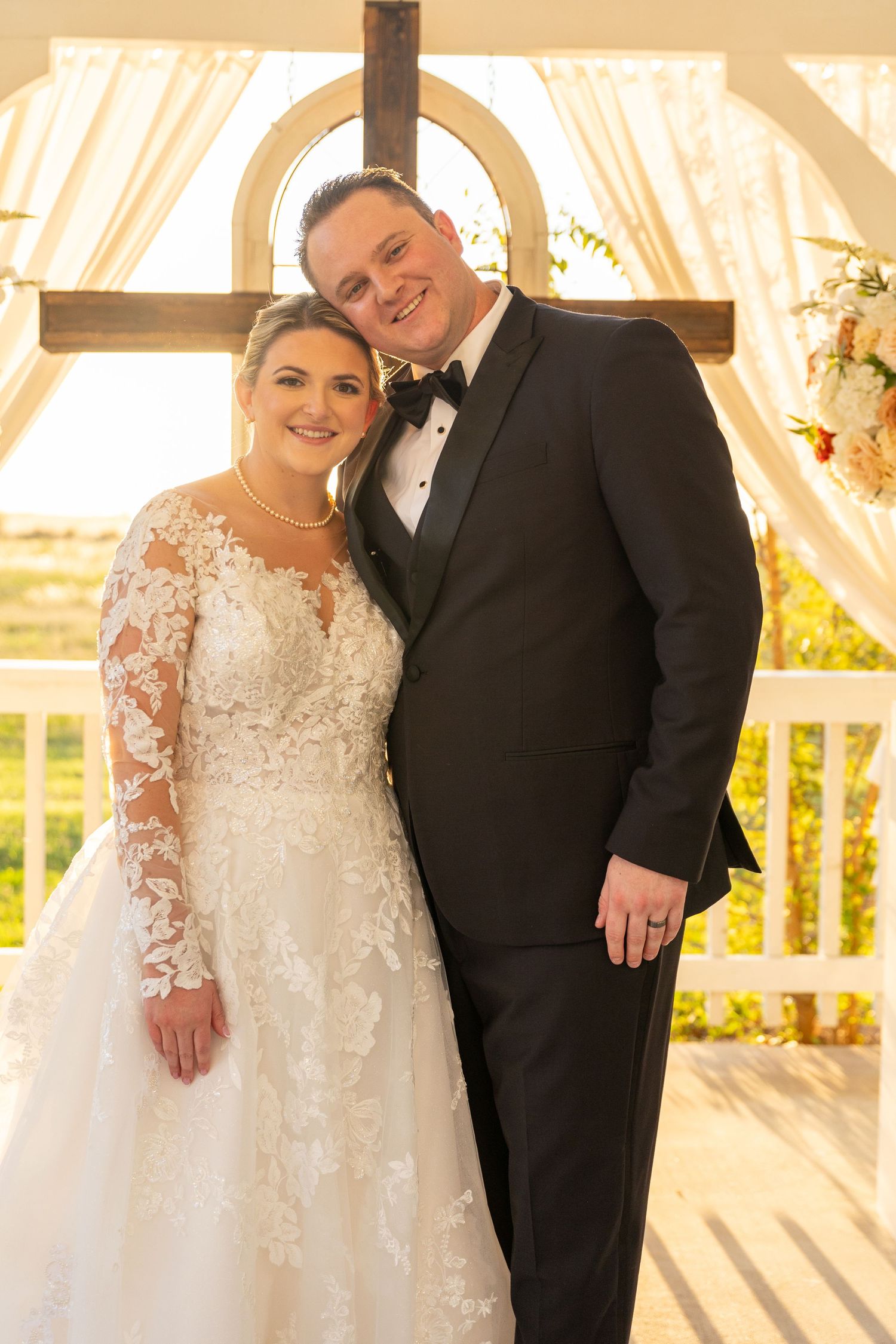Wedding couple posing together under elegant white draped backdrop.