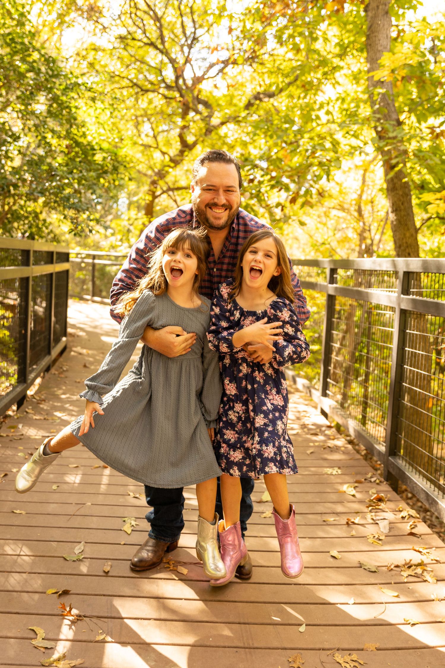 Playful family photo session on wooden deck with children laughing in golden autumn light.