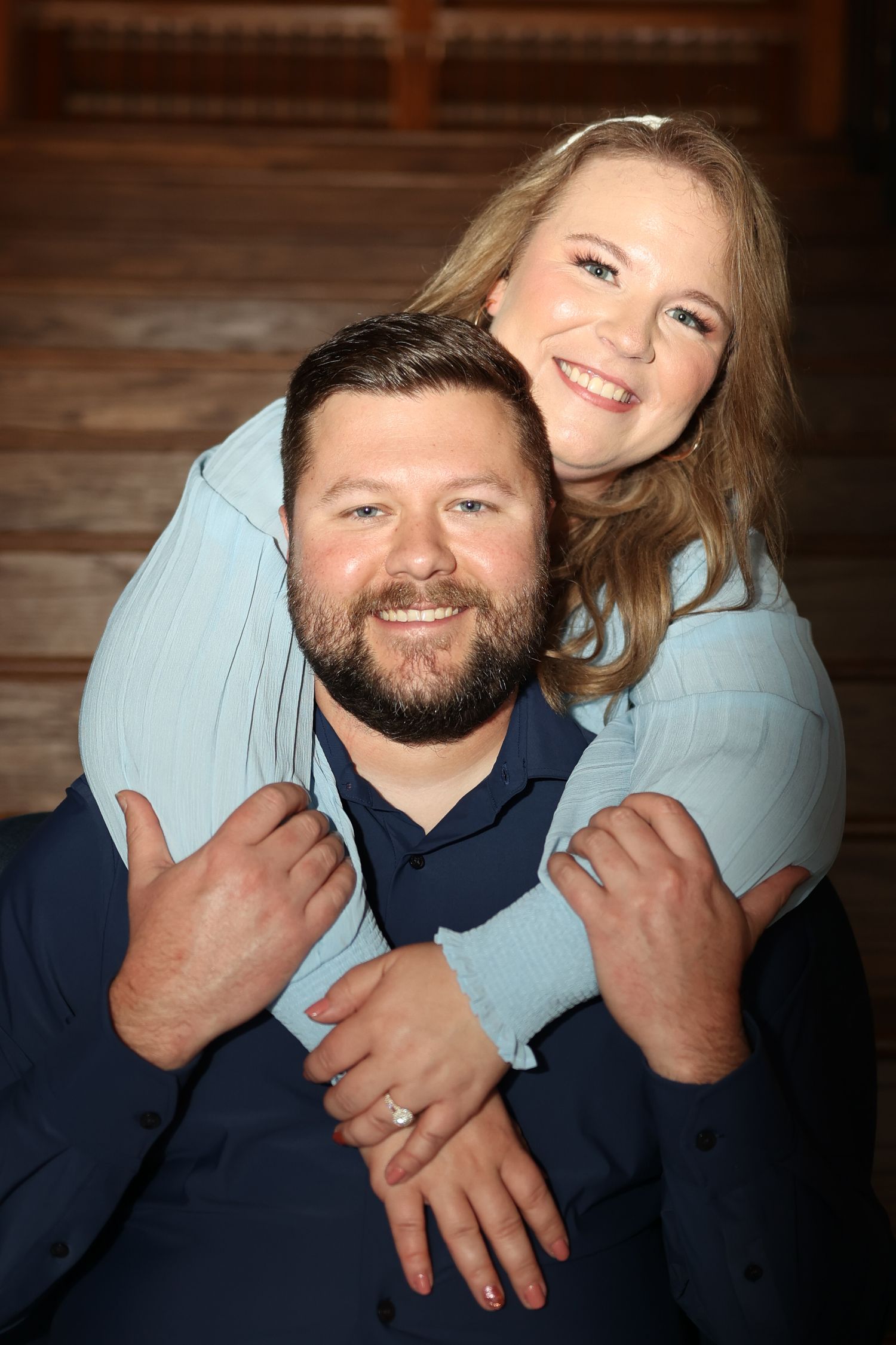 Intimate indoor portrait of couple sharing tender moment against wooden background.