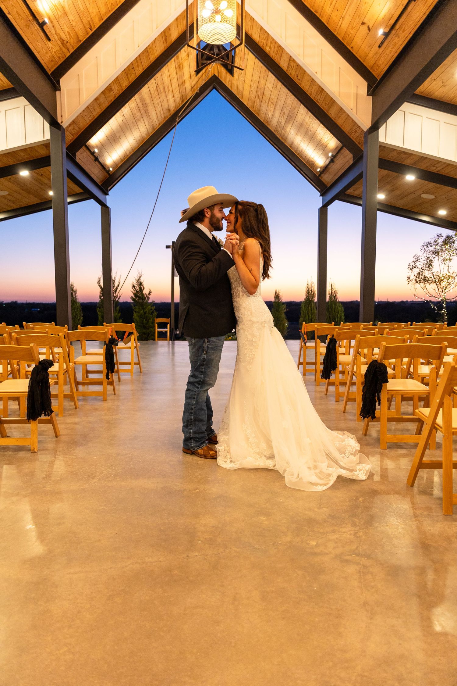 Elegant wedding venue interior with wooden beams and atmospheric lighting during sunset.
