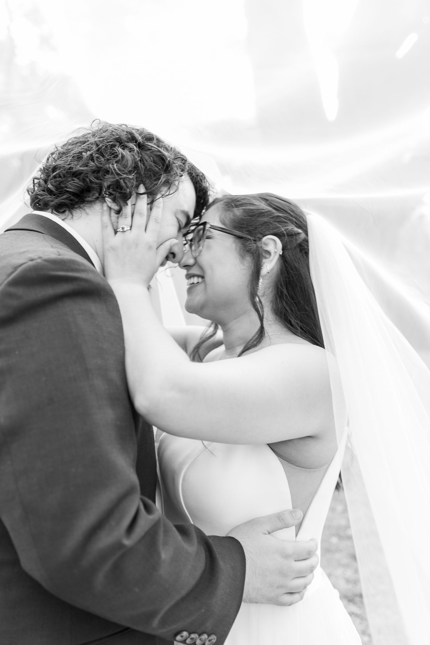 An intimate black and white portrait of a couple sharing a loving embrace during their wedding ceremony.