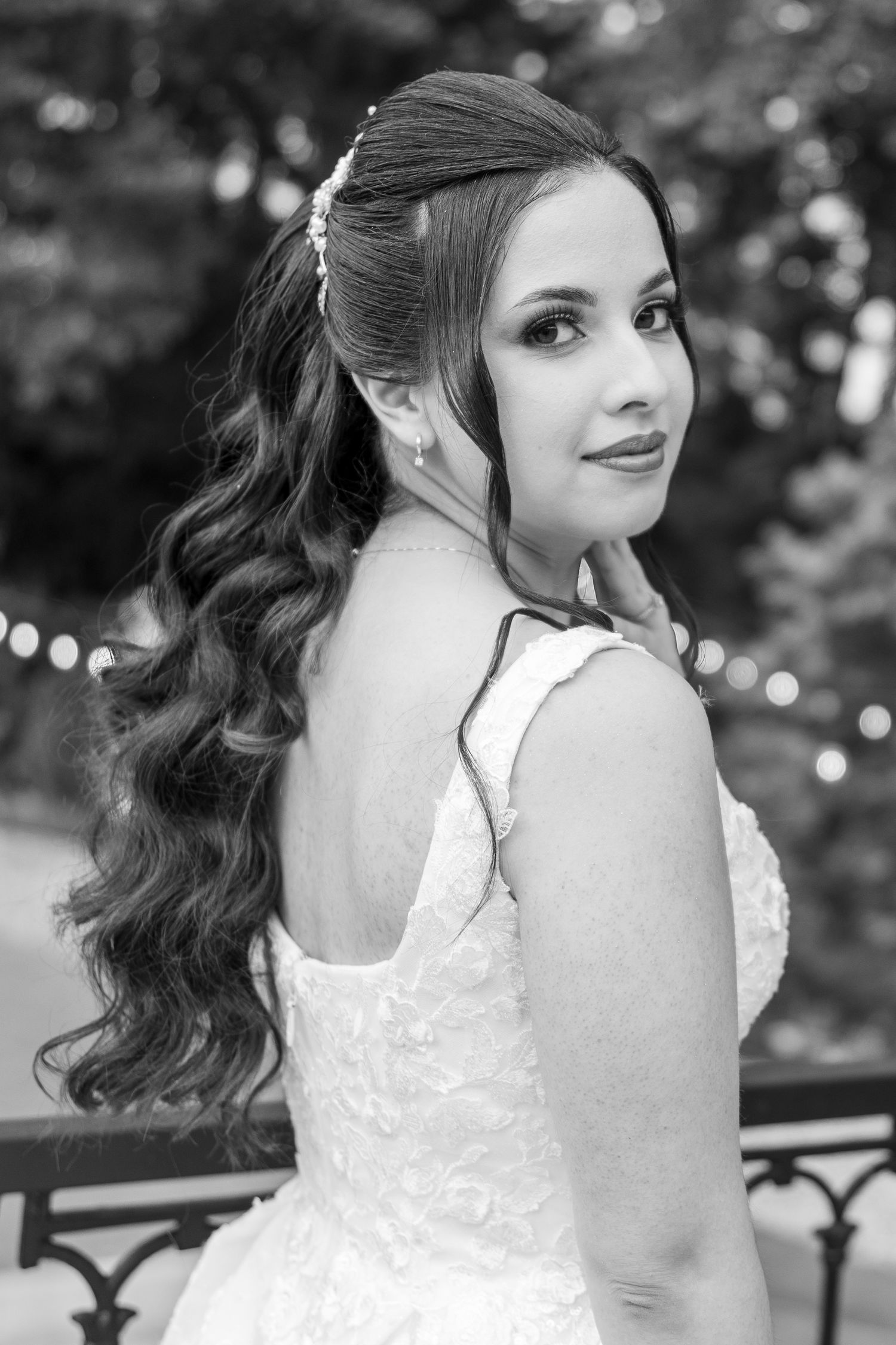 Bride in white lace dress poses for black and white portraits with flowing curled hair.