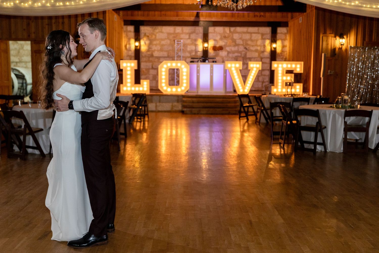 Reception venue with illuminated LOVE sign and romantic lighting.