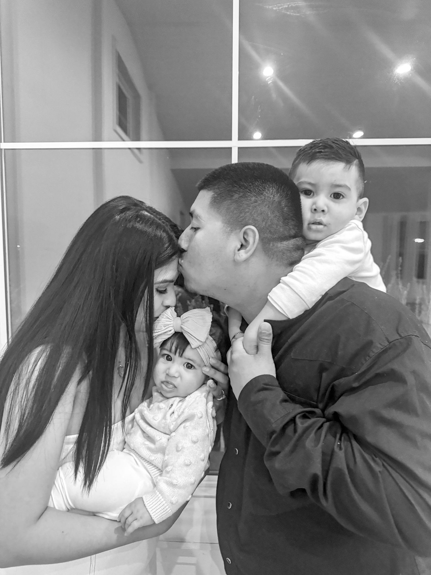 Intimate black and white family moment captured indoors with tender expressions.