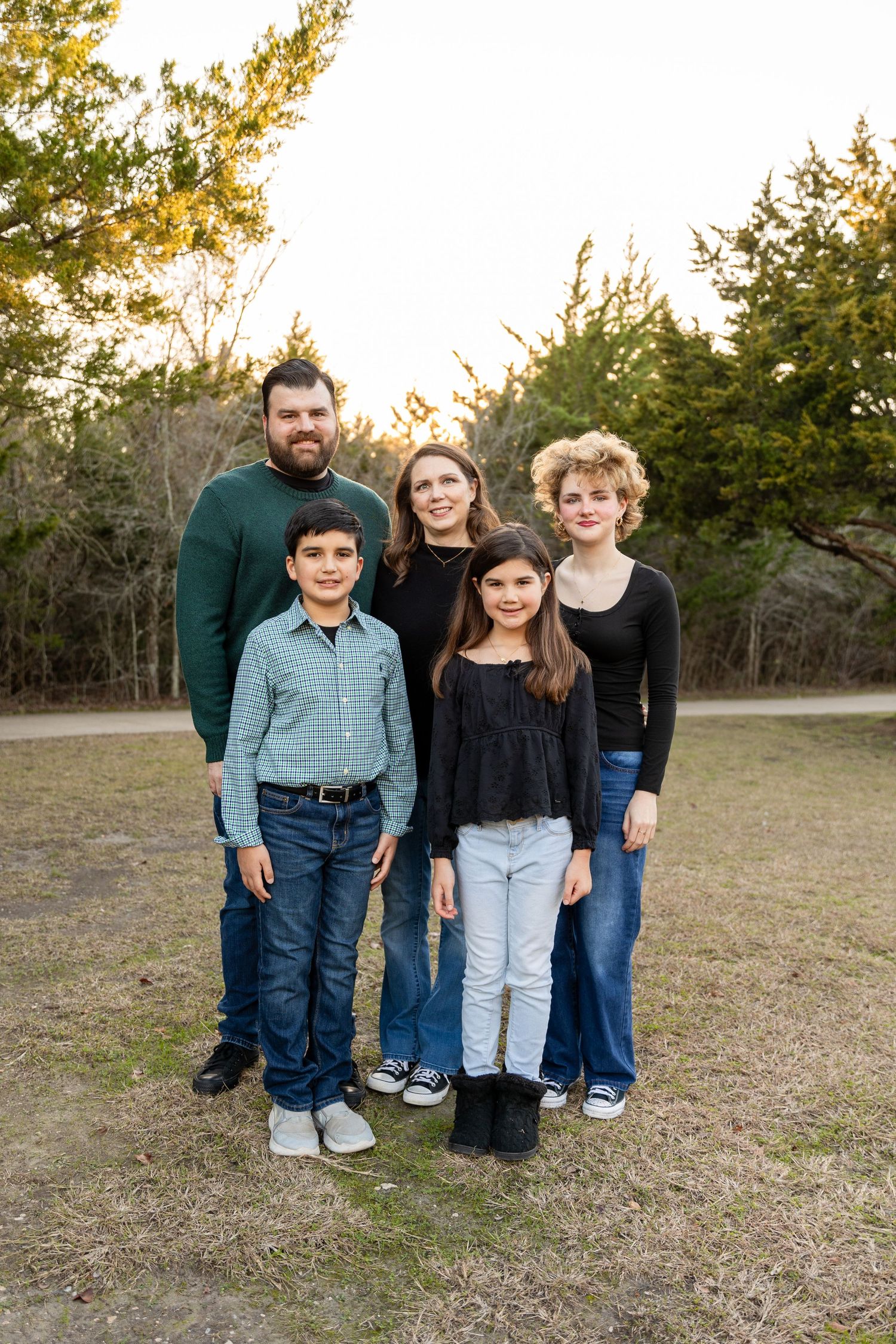 Casual outdoor family portrait in front of autumn trees and natural landscape.
