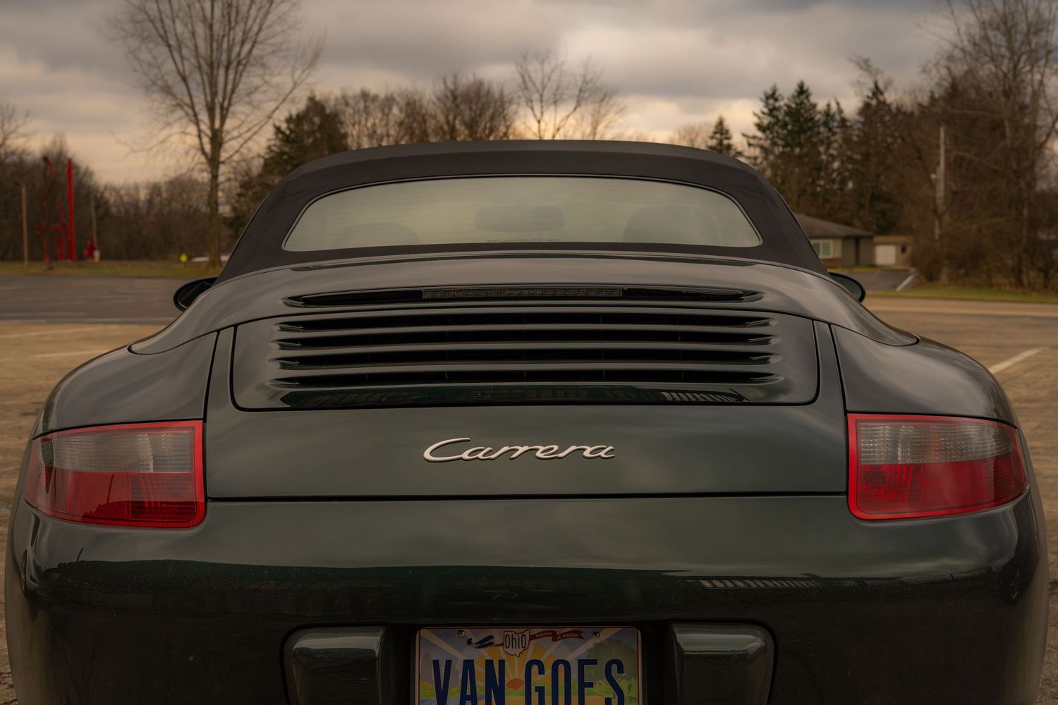 Rear view of dark green Porsche Carrera convertible with VAN GOES license plate.