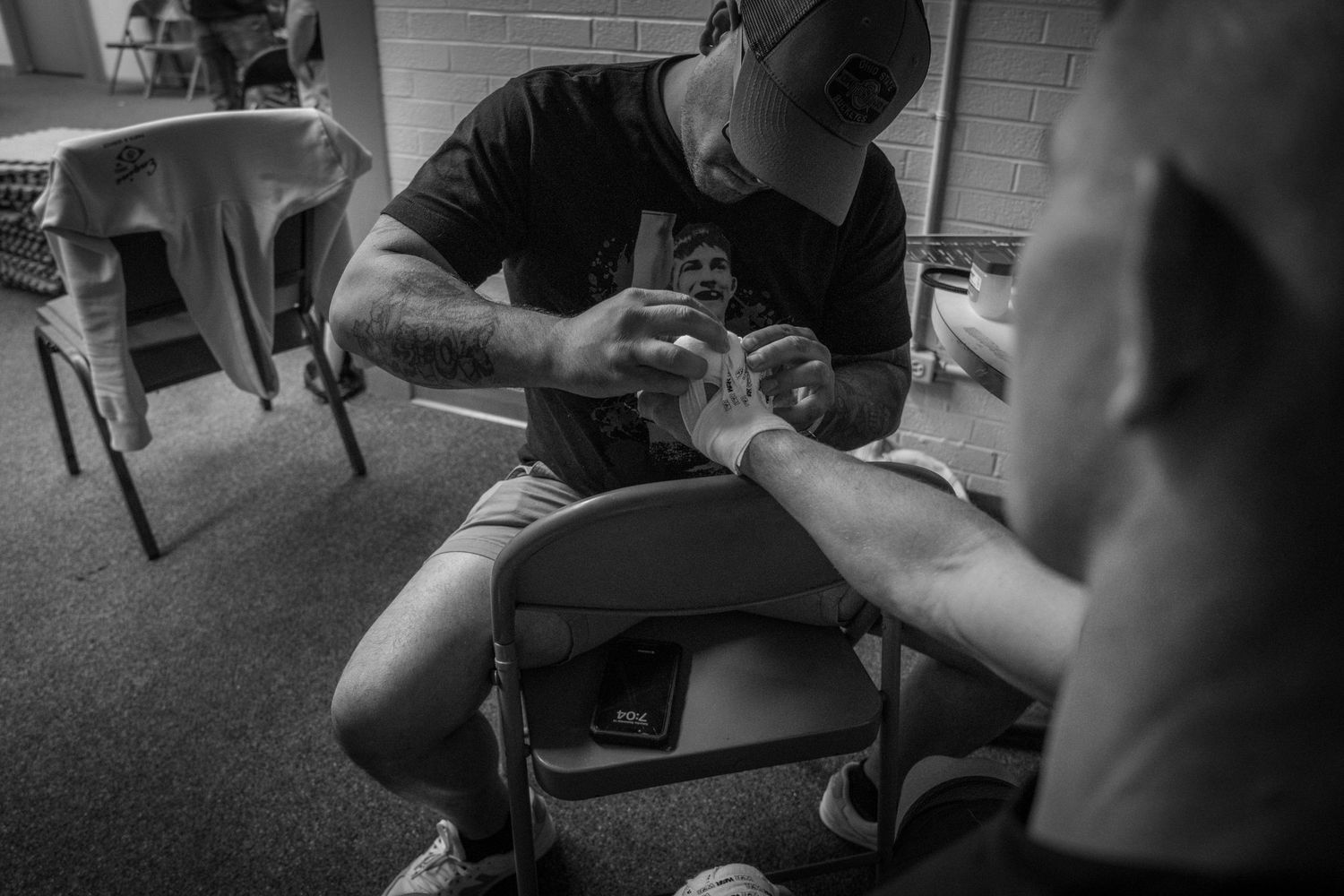 Black and white photo of trainer wrapping athlete's hands in preparation for boxing.