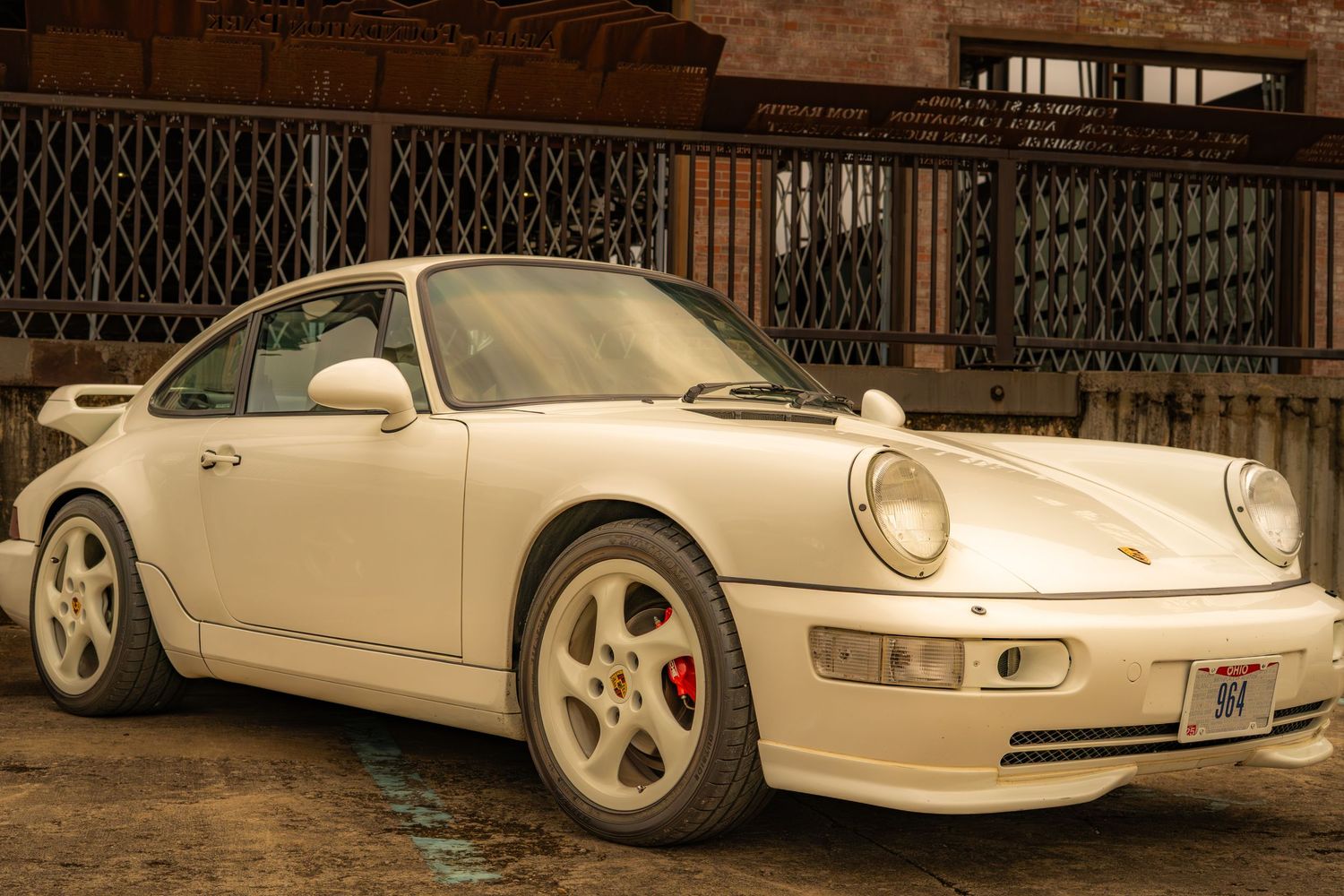 Classic white Porsche 911 sports car parked on urban street with vintage architecture.