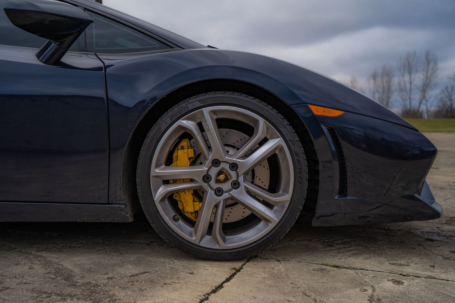 Close-up of gray Lamborghini wheel with yellow brake calipers and five-spoke alloy rim.