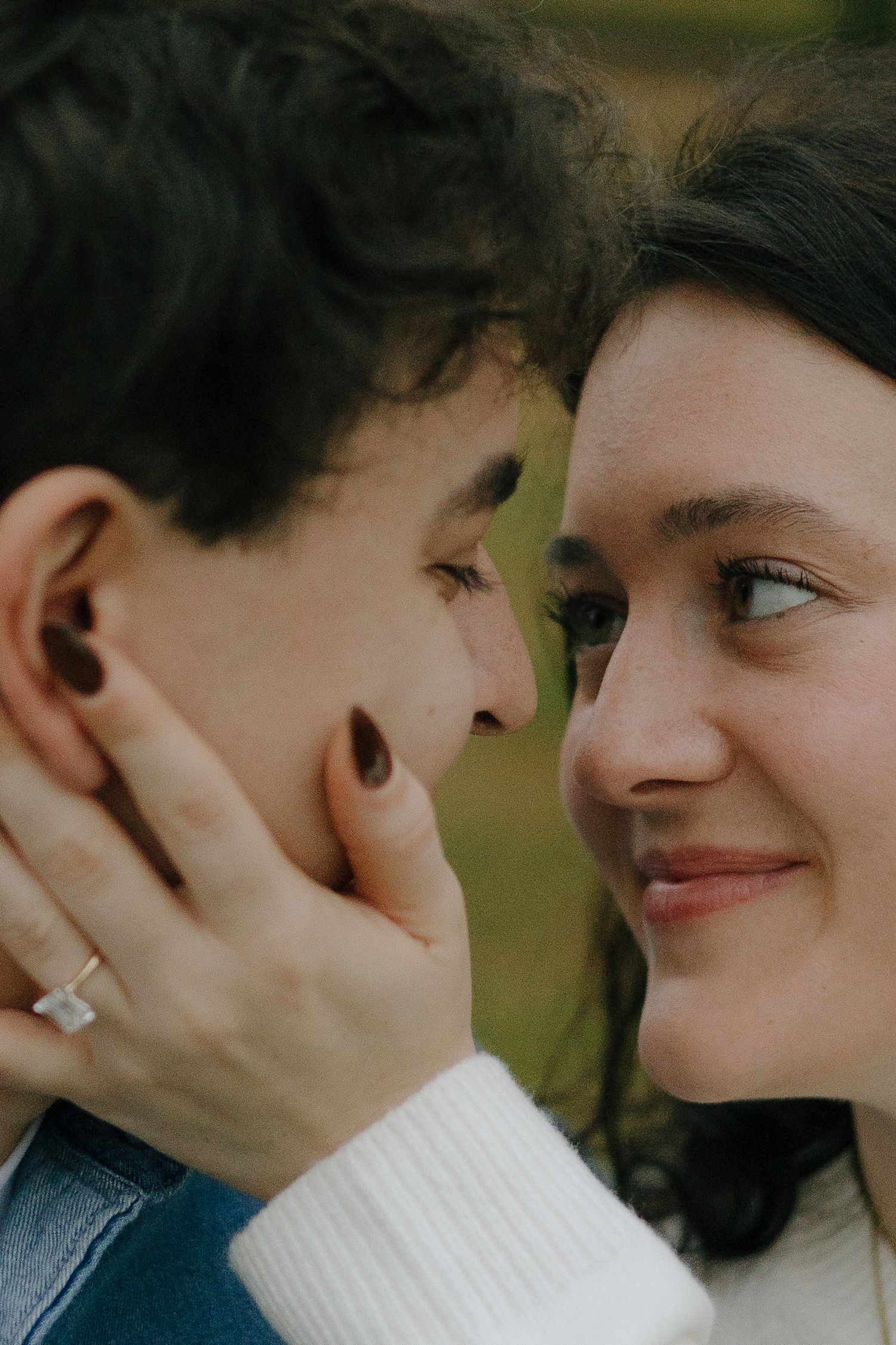 An intimate close-up portrait of a couple sharing a tender moment outdoors.