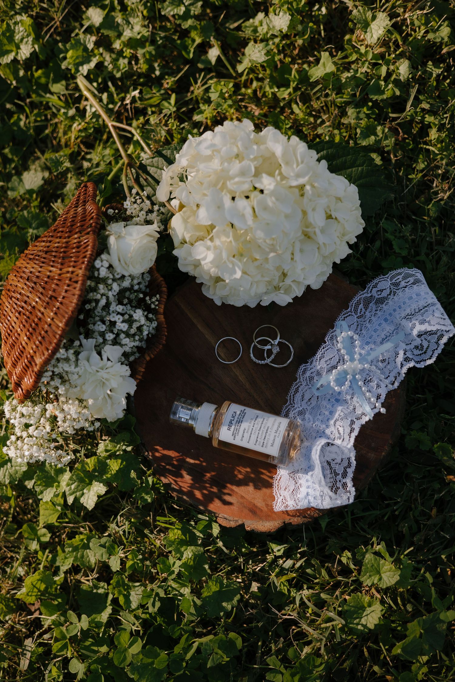 Wedding details including rings, lace, and white hydrangeas arranged on a dark surface.