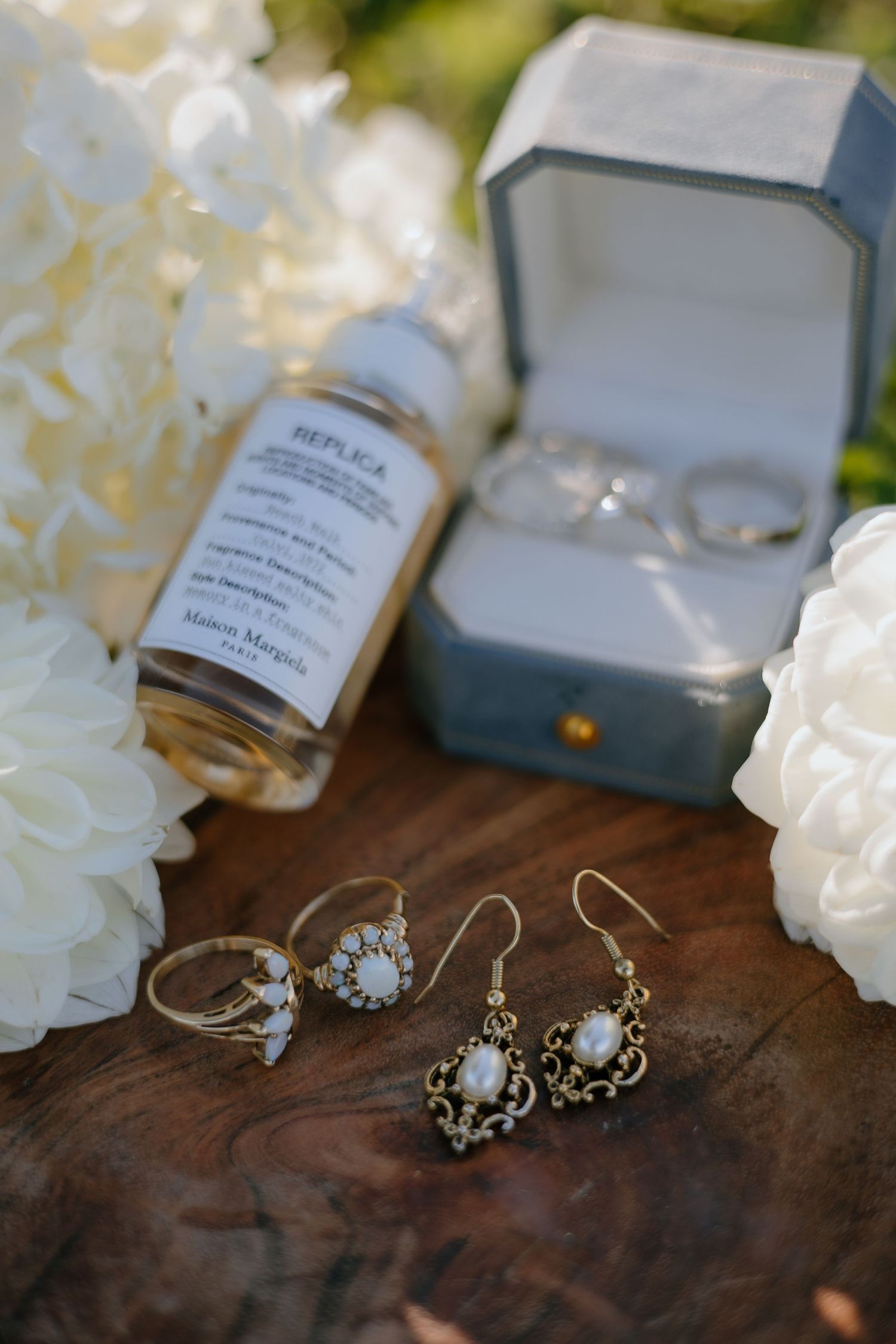 Delicate vintage-style jewelry pieces including earrings and necklaces displayed on rustic wooden surface with soft lighting.