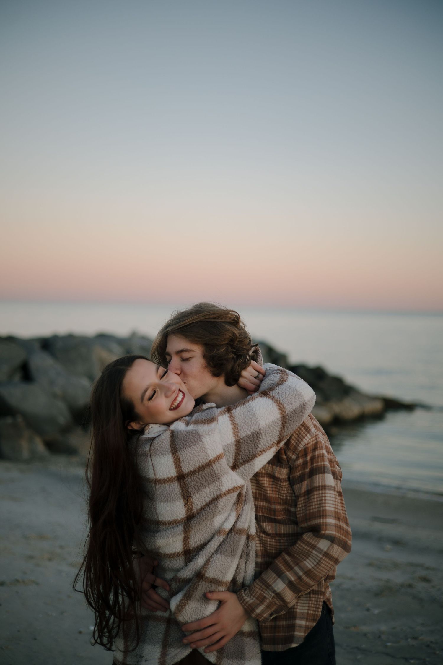 Two people share an intimate moment on the beach during sunset.