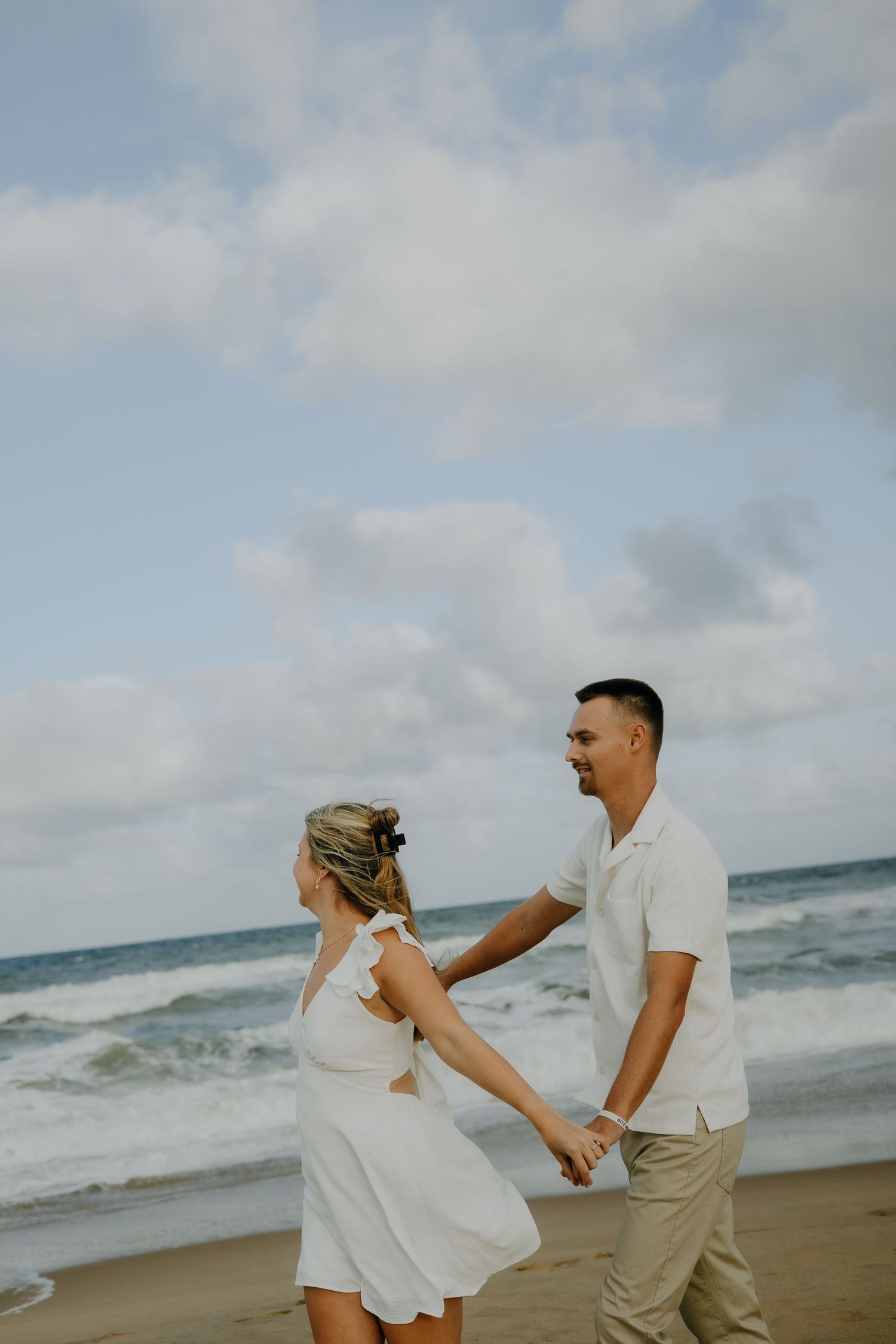 A romantic dance sequence on the beach with a couple in white and khaki outfits.