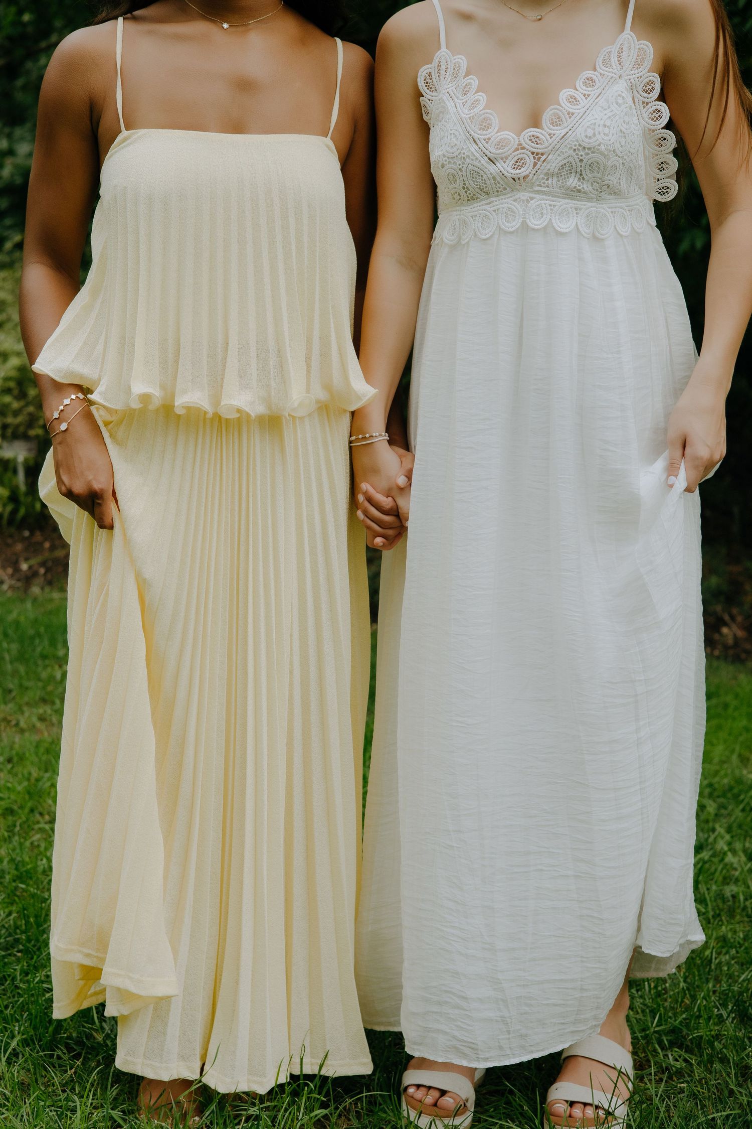 Close-up detail of white and cream summer dresses with delicate lace trim and pleating.
