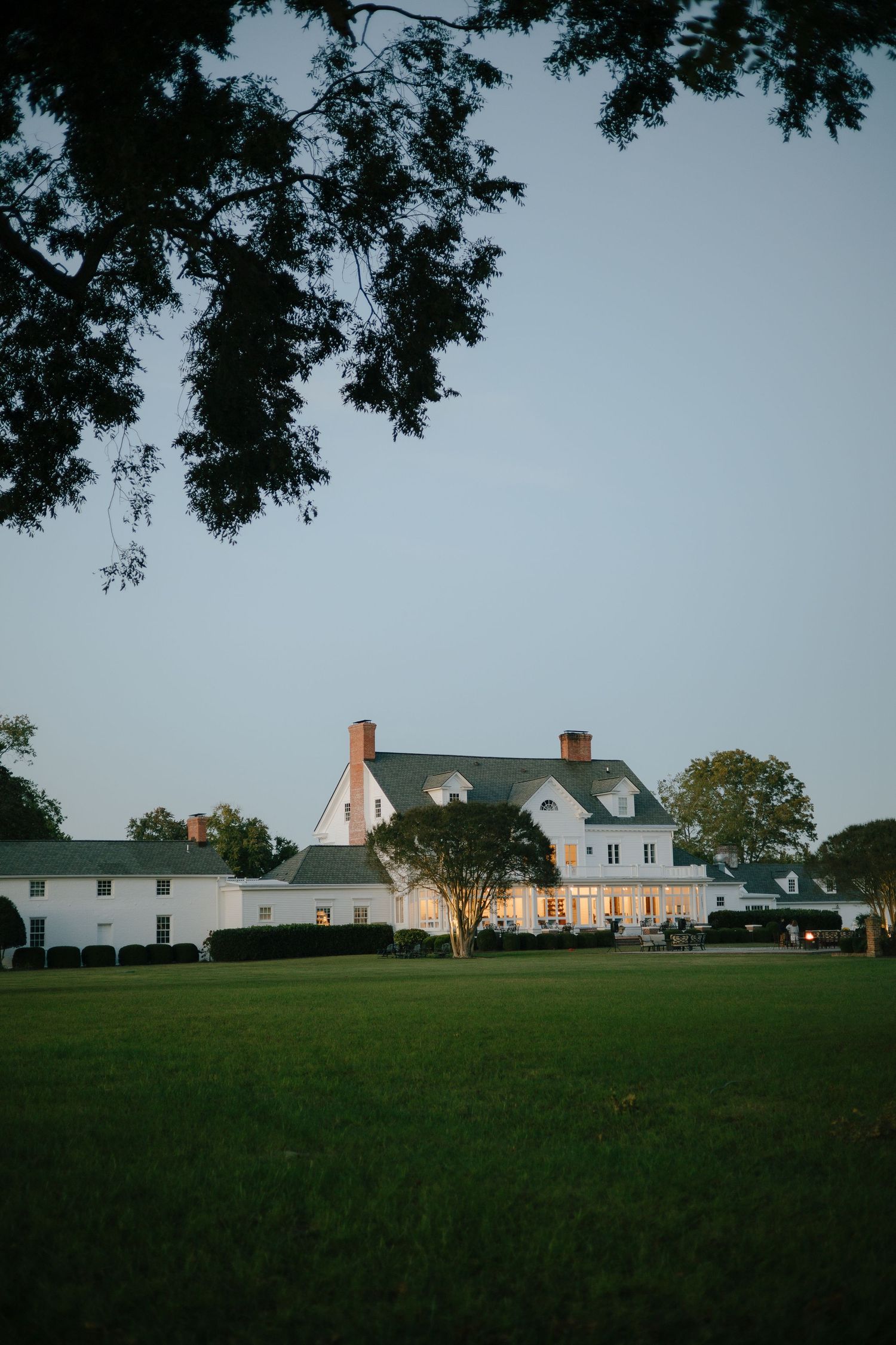 White farmhouse buildings on rolling green hillside at dusk.
