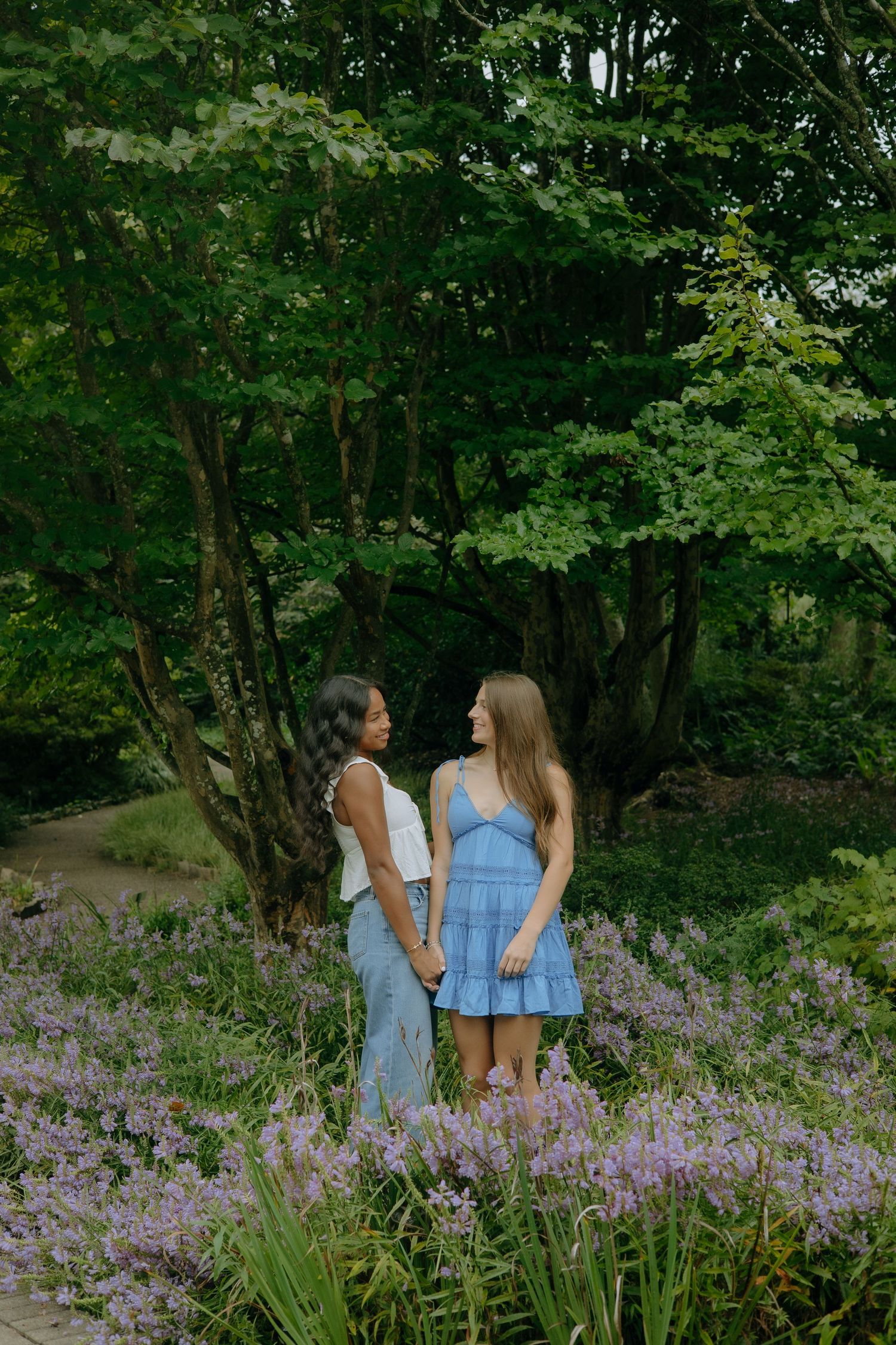 Friends standing together among purple wildflowers in a scenic outdoor setting.