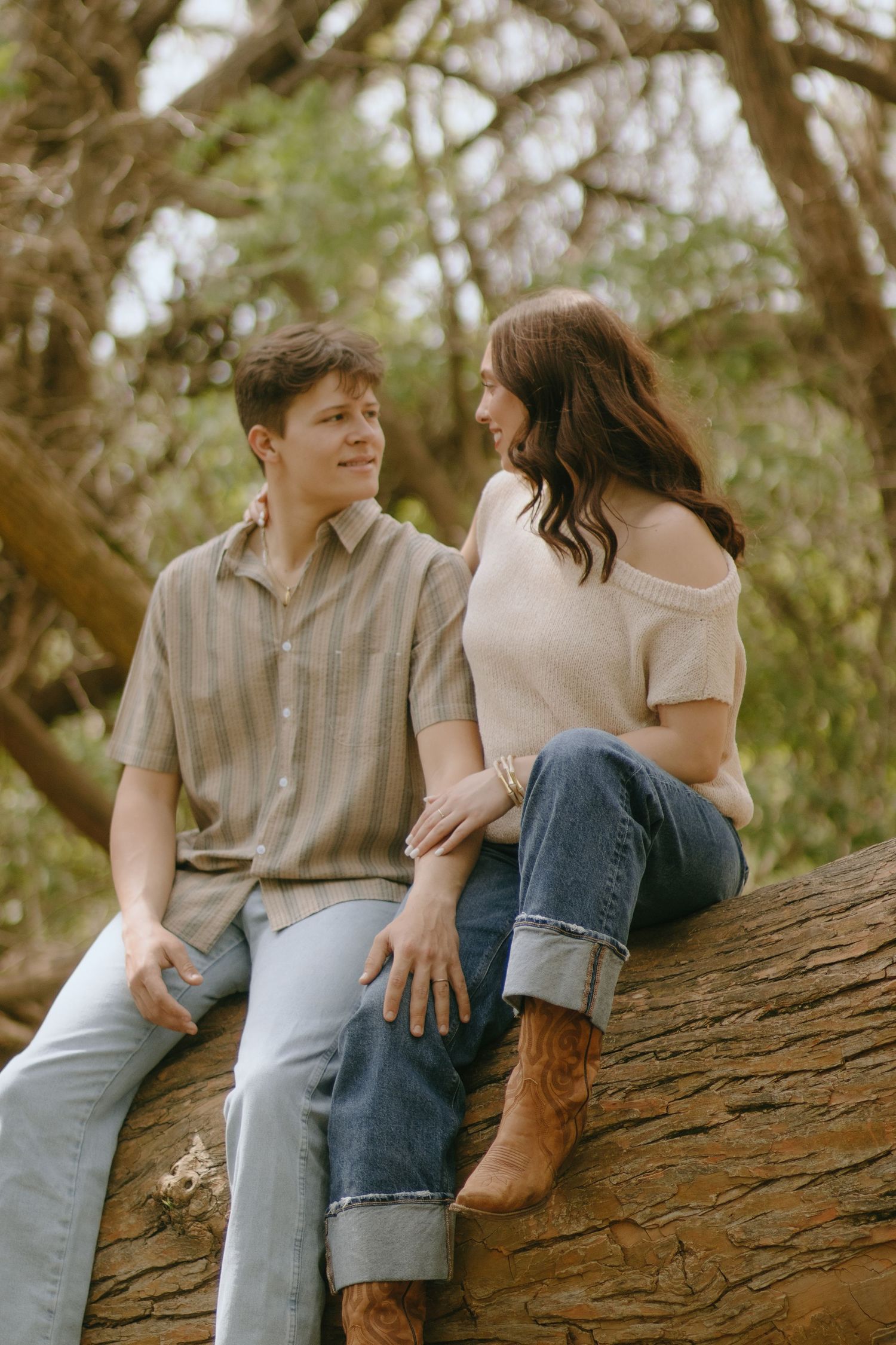 Two people sharing a moment while sitting on a large fallen log.