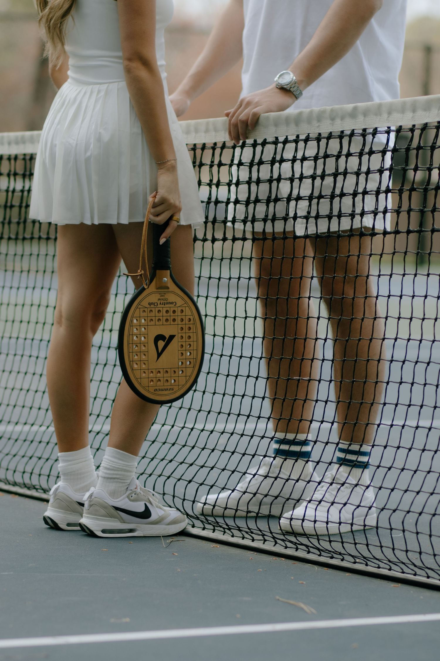 Tennis rackets and feet in white shoes visible near a tennis court net.