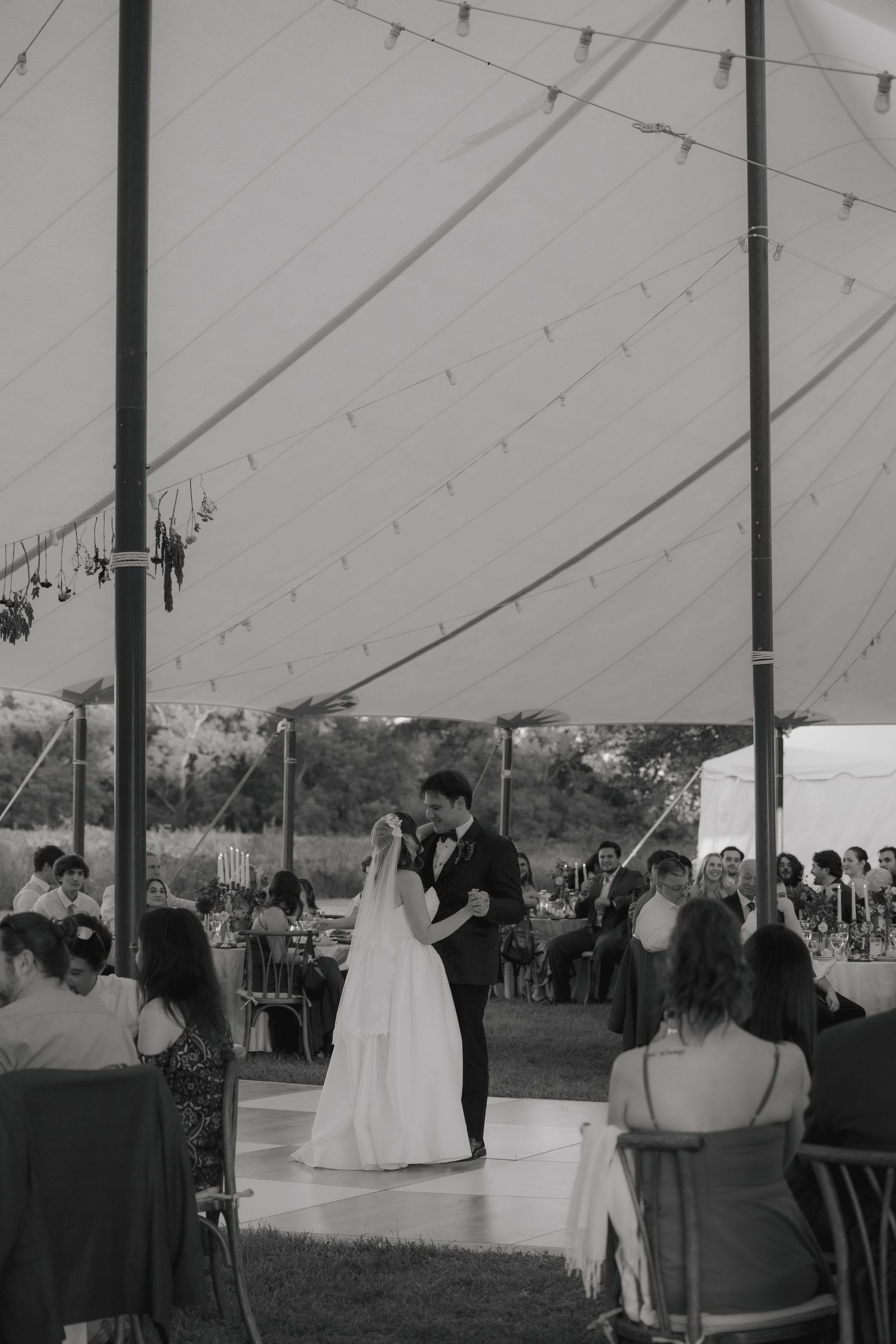 Black and white photo sequence showing a couple's first dance under a large outdoor wedding tent during their reception.